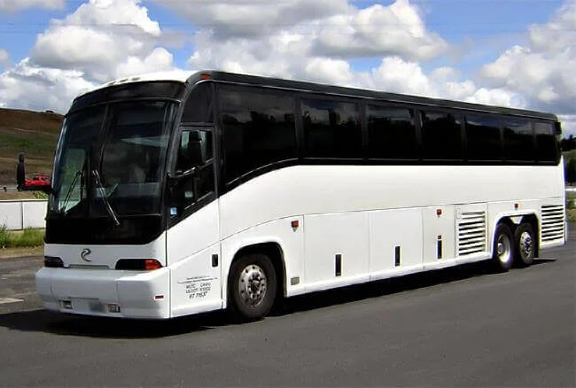 A large white and black motorcoach bus parked on a paved road.