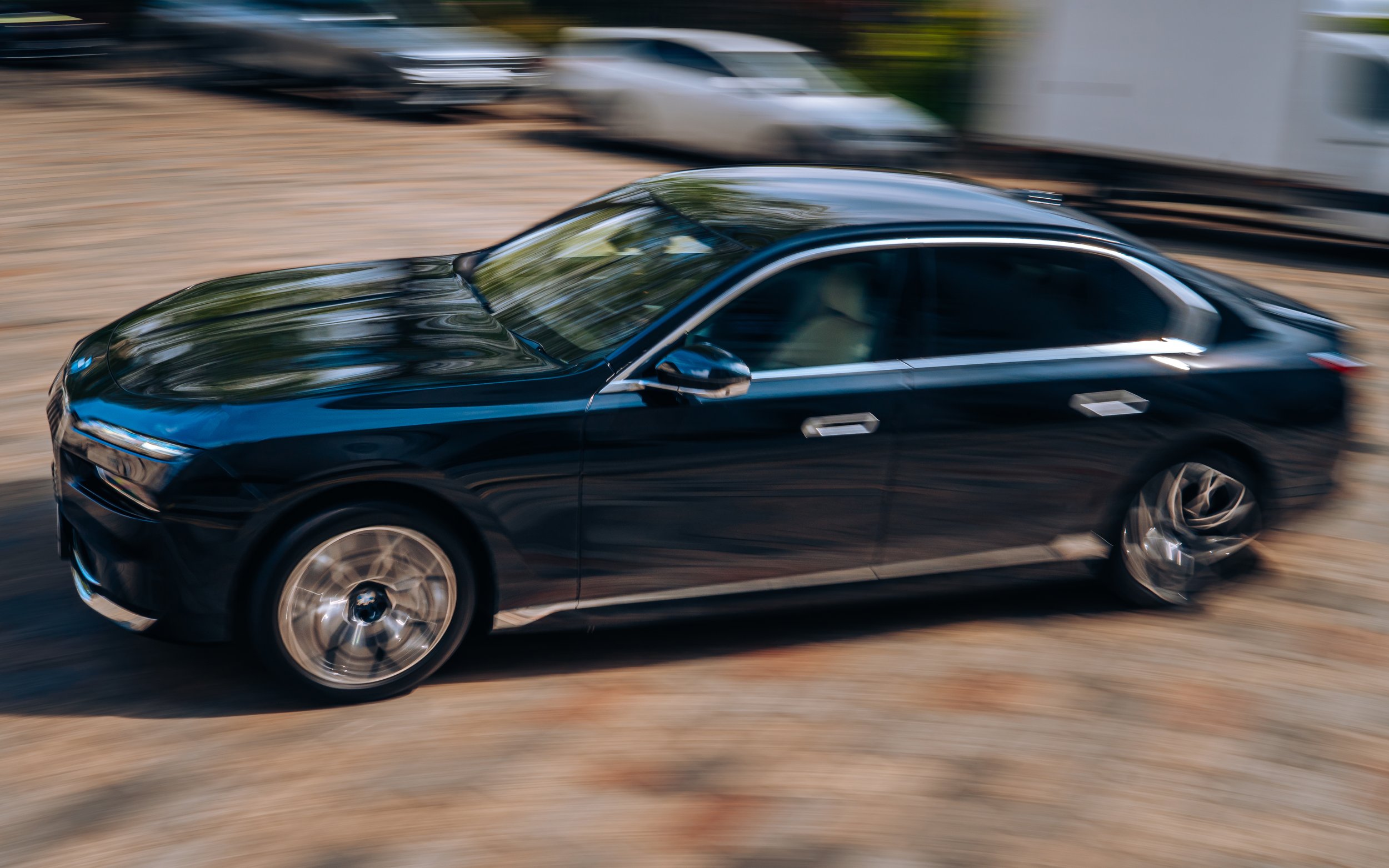 A black sedan car driving on a dirt road with a motion blur effect.