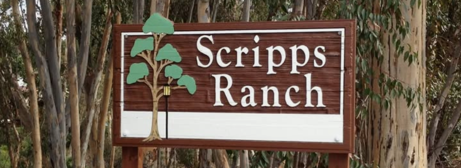 Wooden sign reading 'Scripps Ranch' with a tree illustration, mounted among trees and foliage.