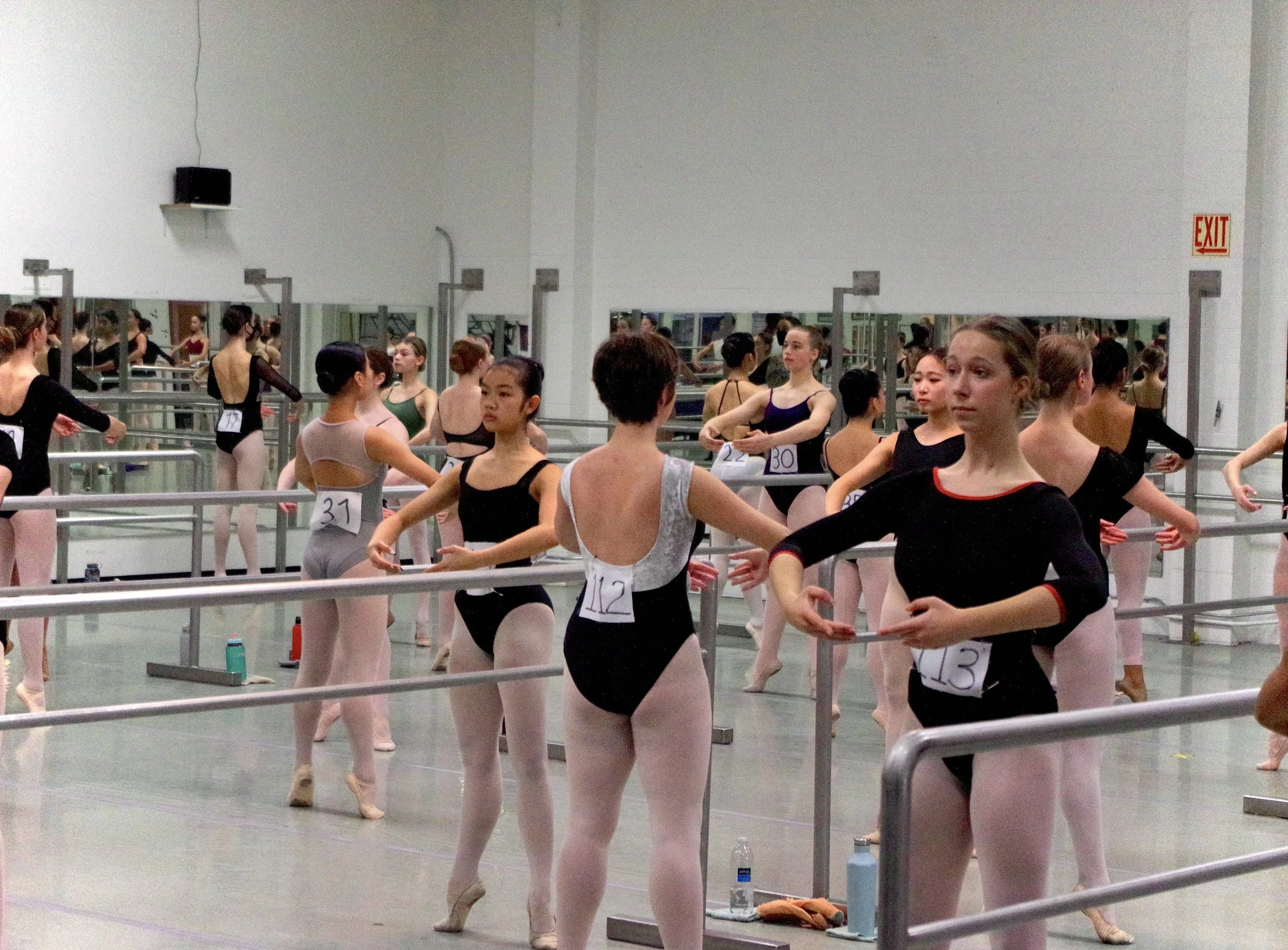 Ballet dancers in practice at a dance studio with mirrors and ballet bars