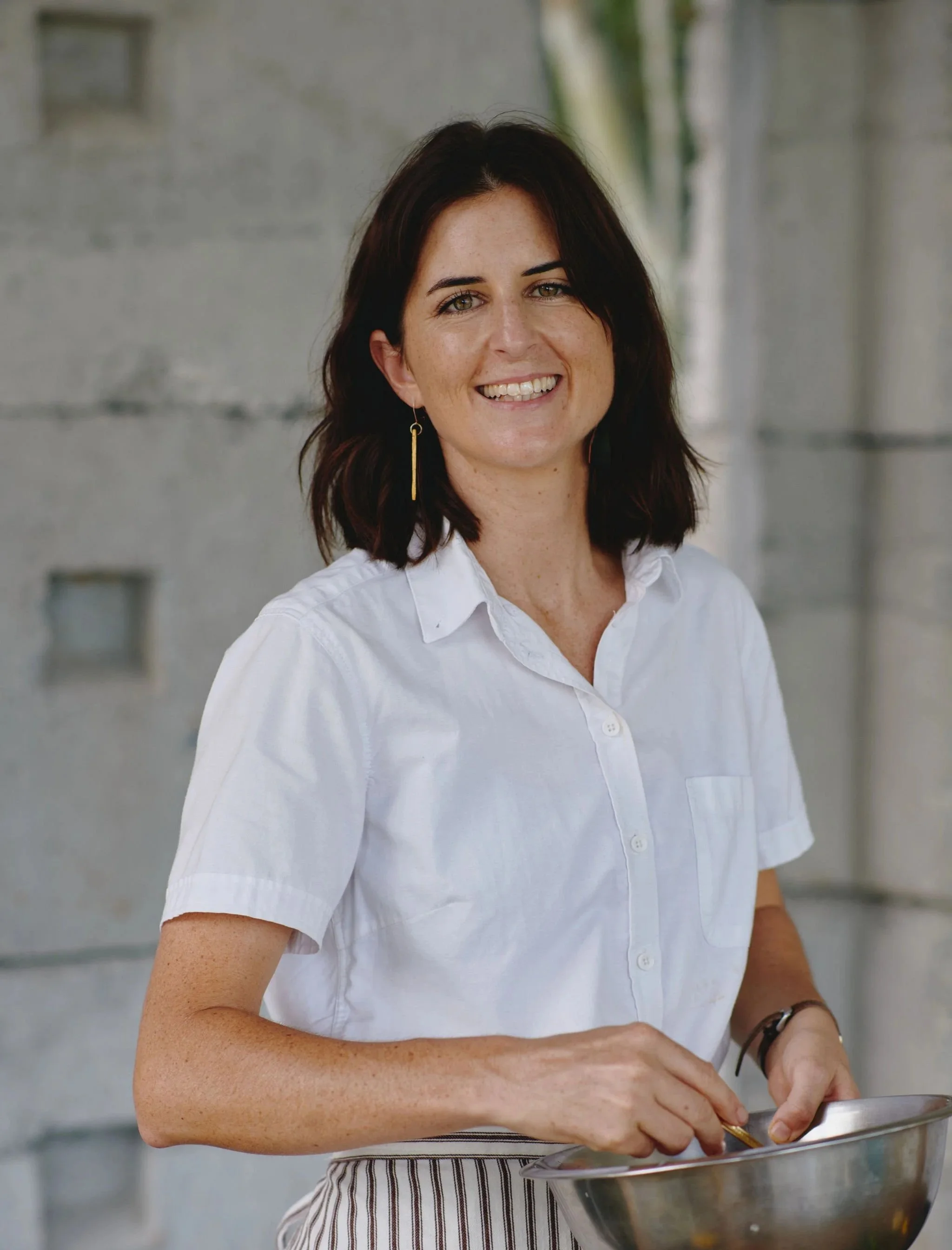 Amy klitscher retreat chef stirring a silver bowl with white collared shirt