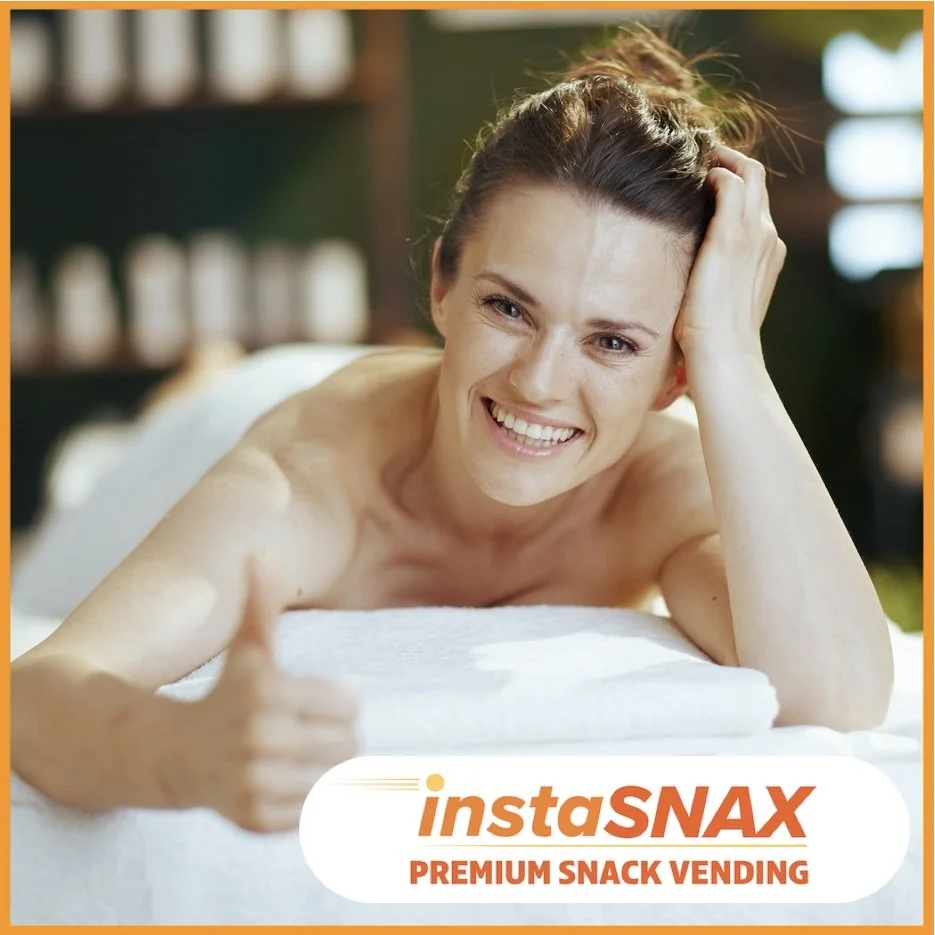 Woman on massage table in salon smiling and giving thumbs up to the camera.