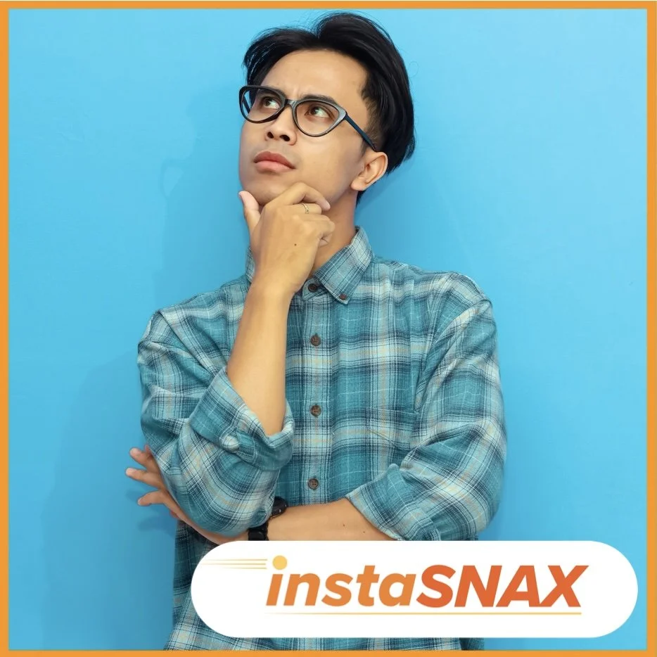 Asian man in blue plaid shirt with hand on chin, looking up and thinking, text instaSNAX premium vending at bottom