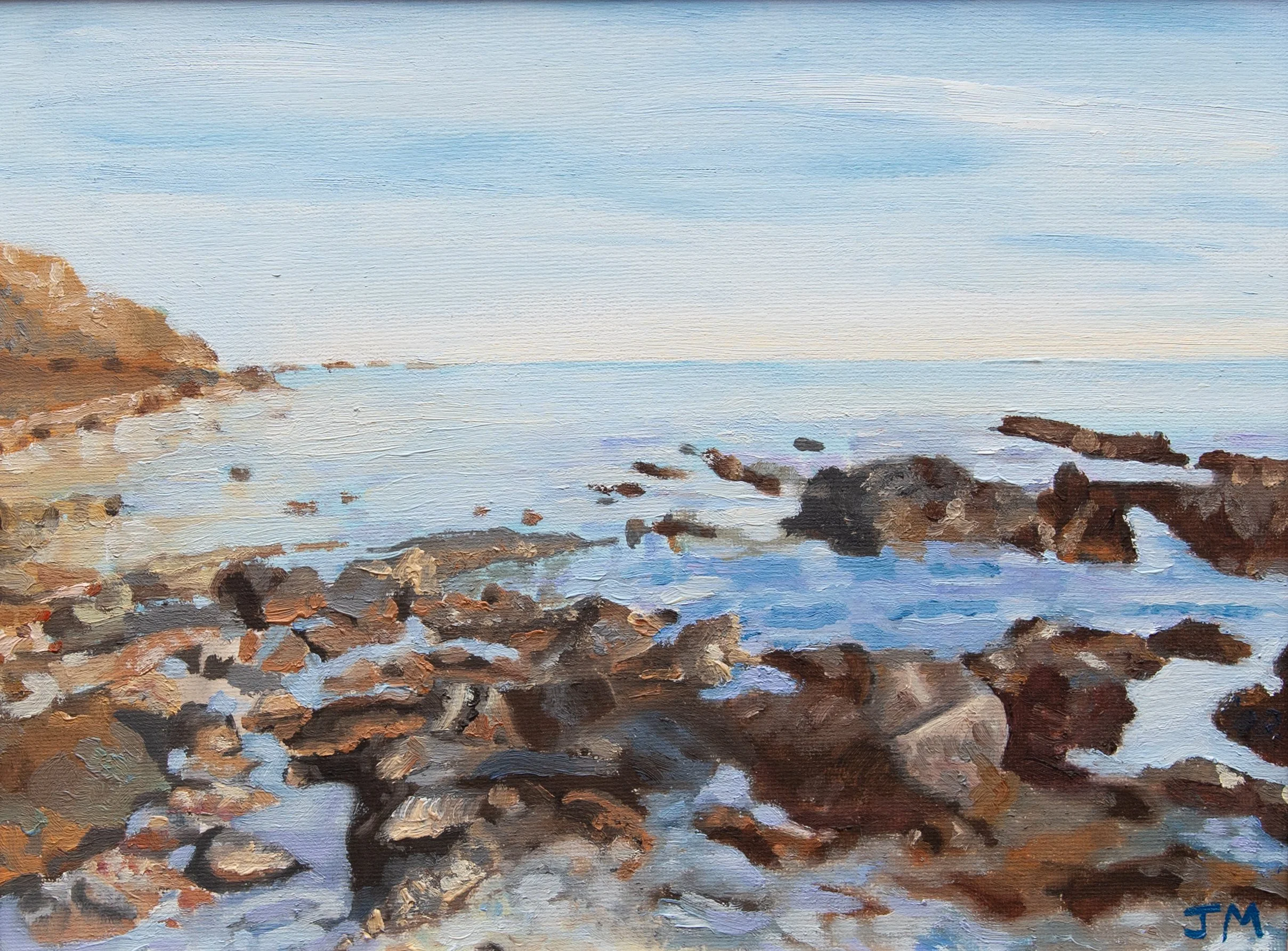 An oil on canvas painting of a rocky shoreline with calm water, distant hills on the left, and a blue sky with light clouds. Rocks on the beach in the foreground.
