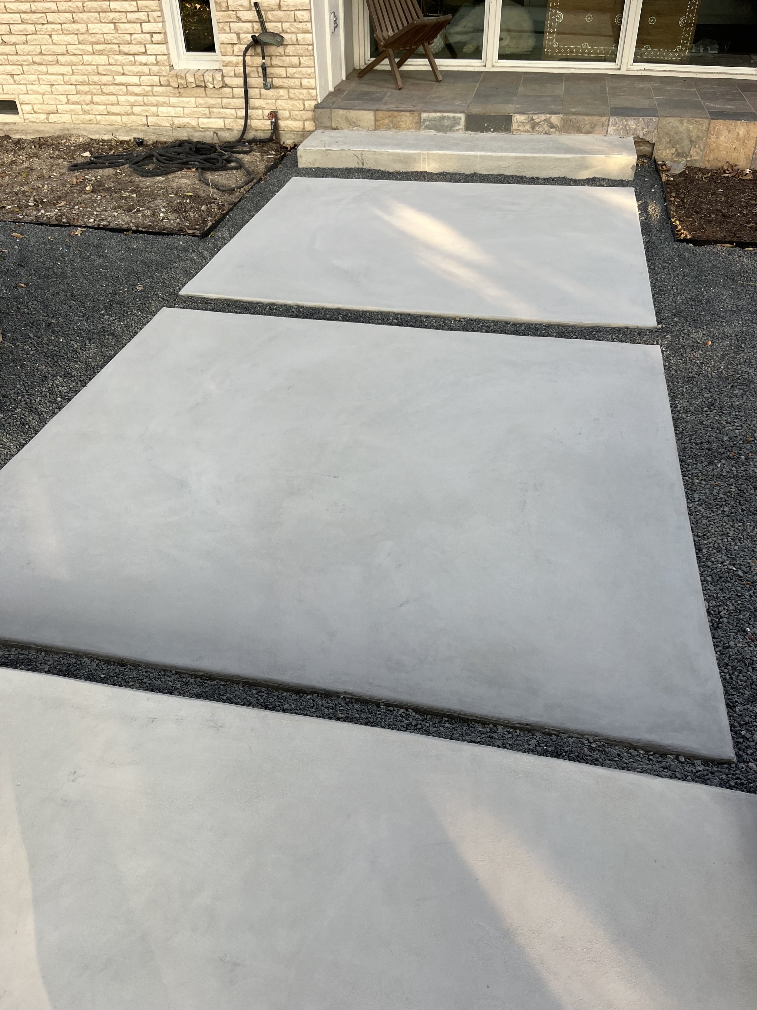 Freshly poured concrete slabs in front of a house, with a staircase leading to the porch.