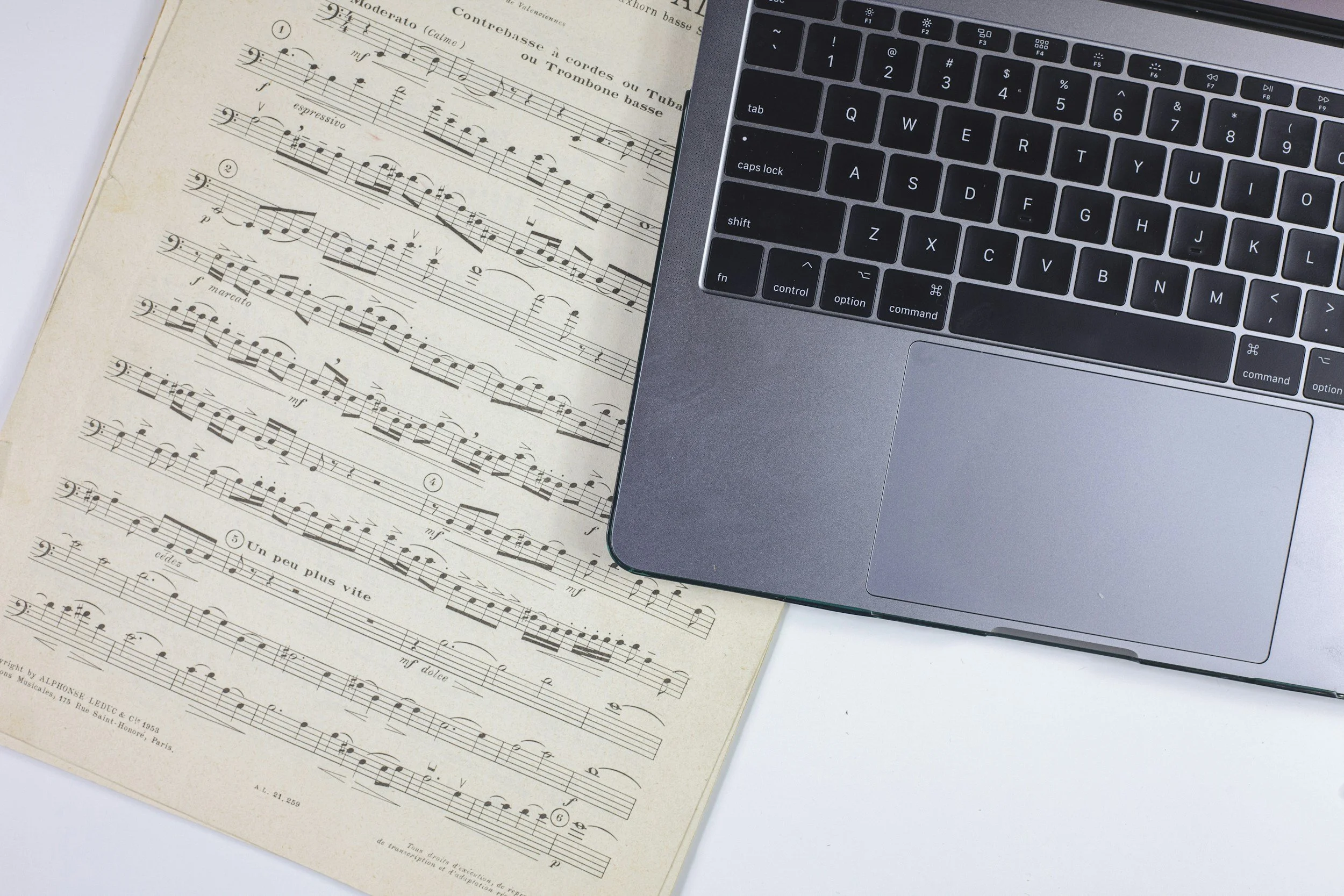 Music sheet with musical notes, and part of a laptop keyboard on the right side of the image.