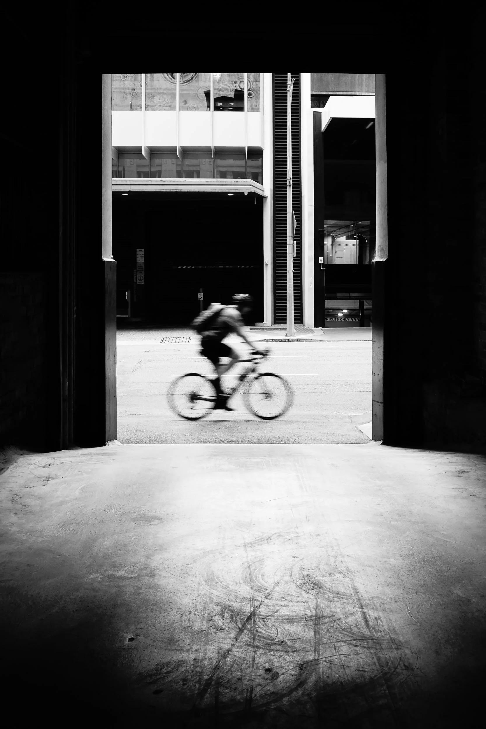 Framing Life's Journey: Through life's subtly open doors, we glimpse fleeting, yet profound moments. As a lone rider cycles past, its a visual reminder that even framed perspectives beautifully reveal ongoing journeys and unseen resilience, eternally