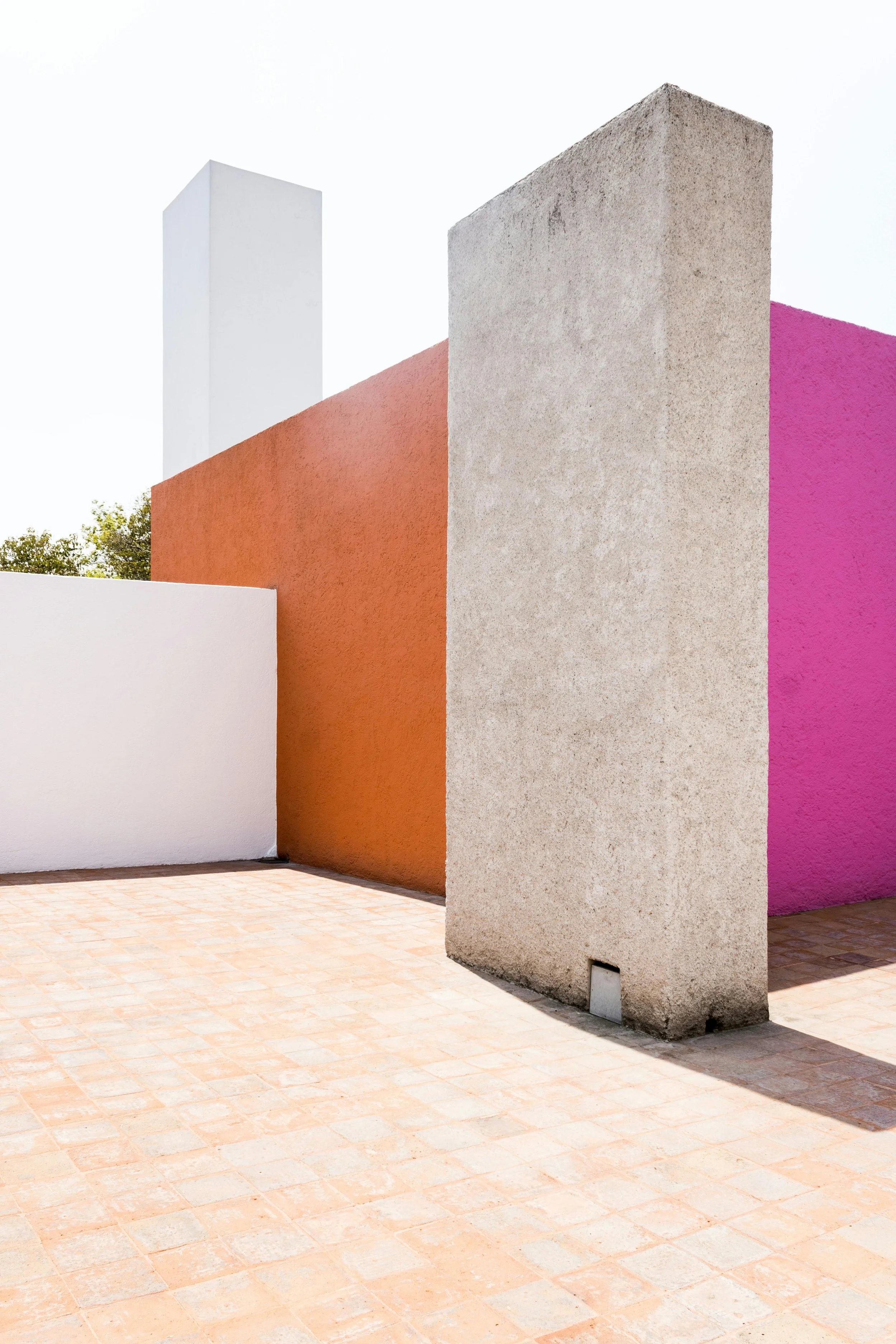 Colorful modern building with white, orange, pink, and beige walls, and a brick-paved ground.