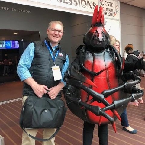 Nick standing next to a man dressed as a bug at a conference.