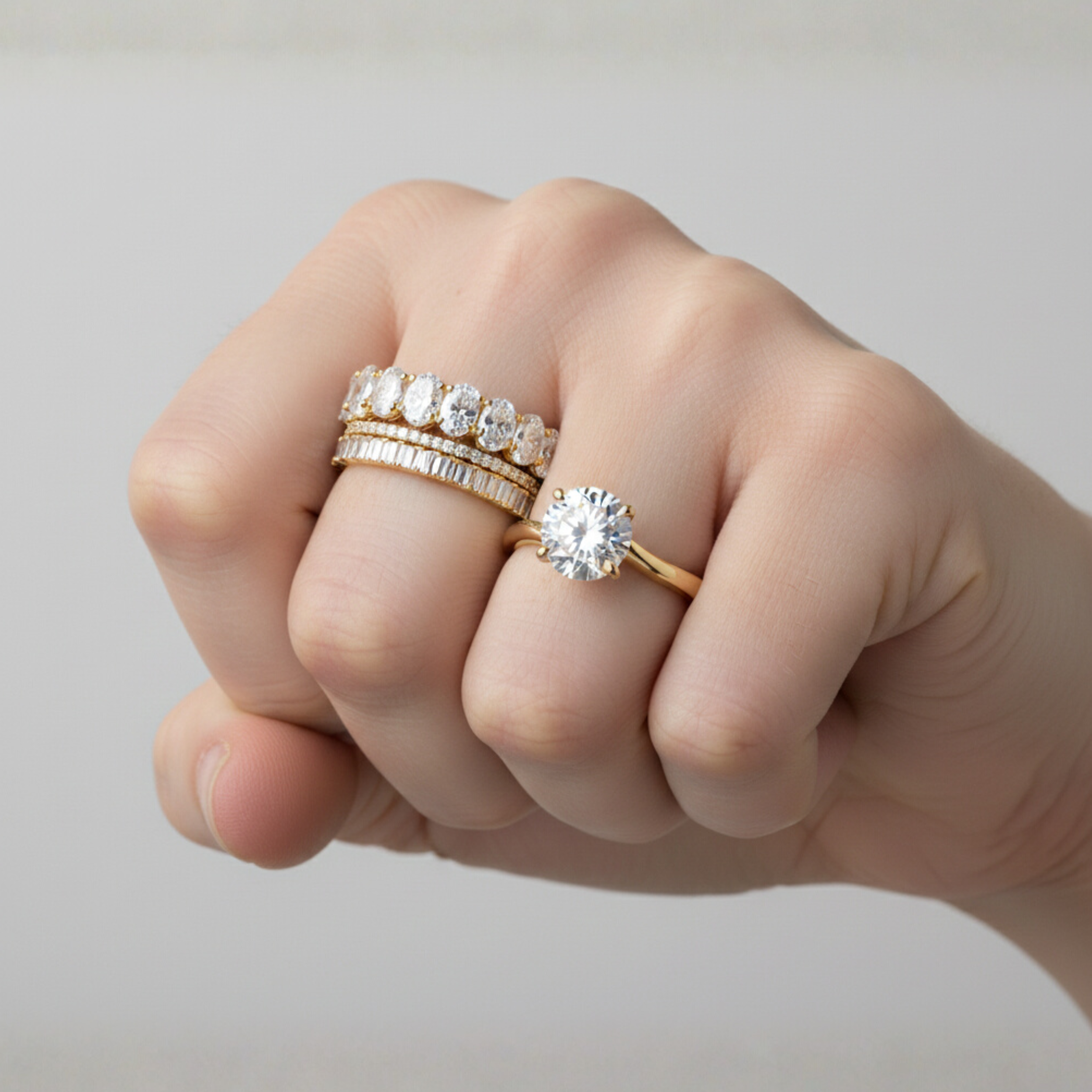 Close-up of a hand with three shiny diamond rings on the ring finger.