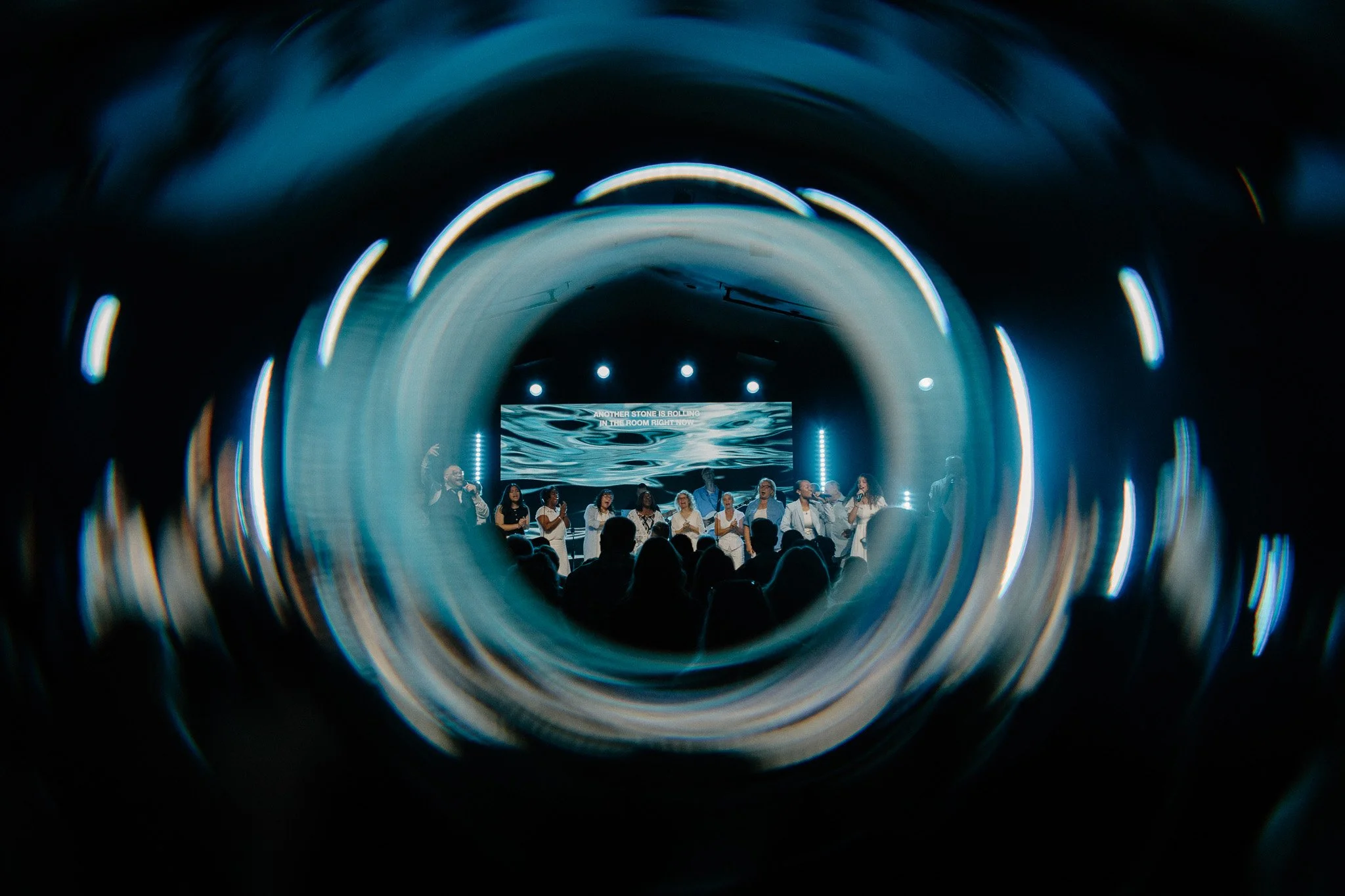 The Bay Church Brentwood Campus Easter Sunday Services with a Chior on stage surrounded by a beautiful swirl effect