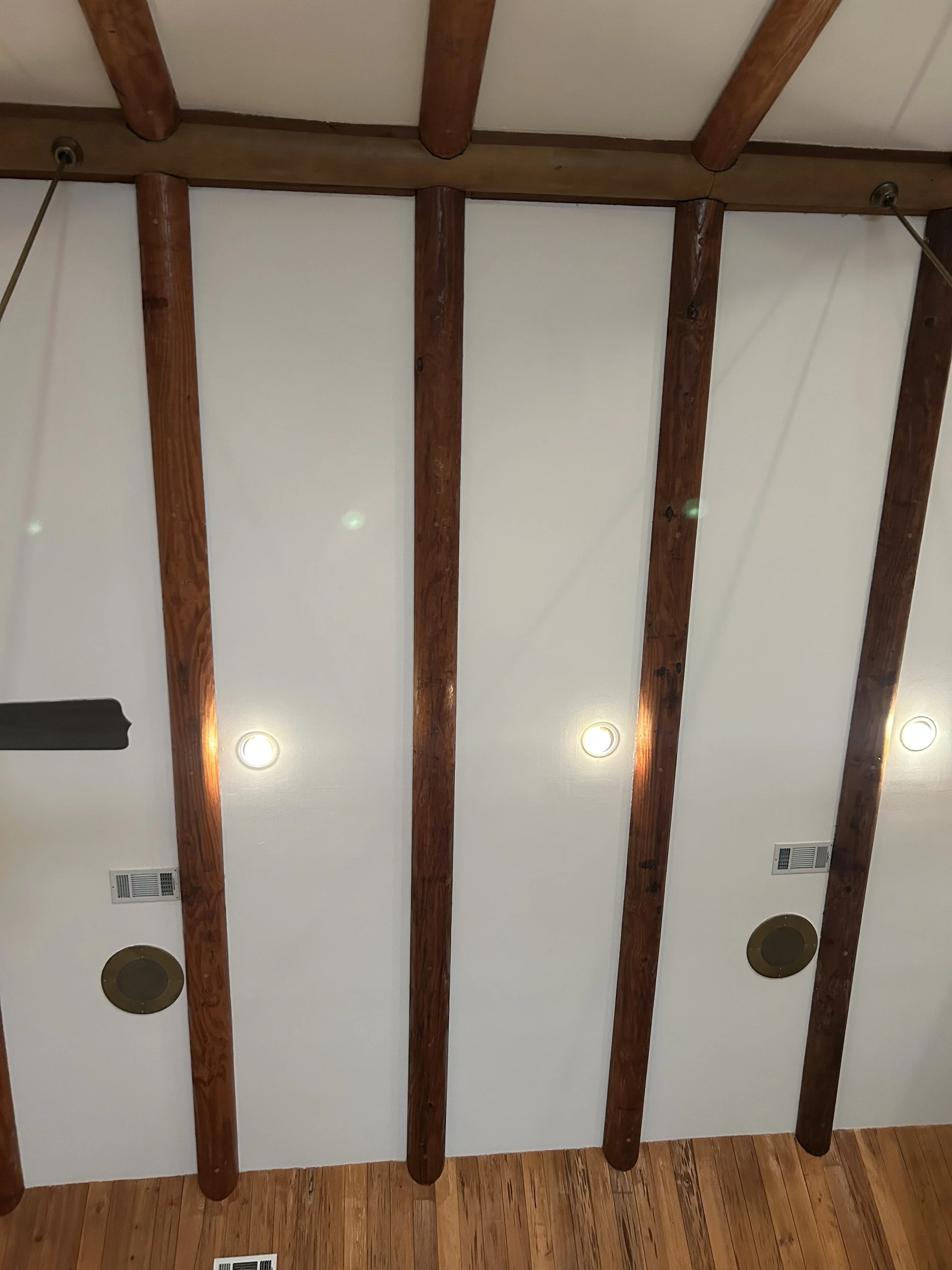 Ceiling with exposed wooden beams, recessed lighting, and wall vents.