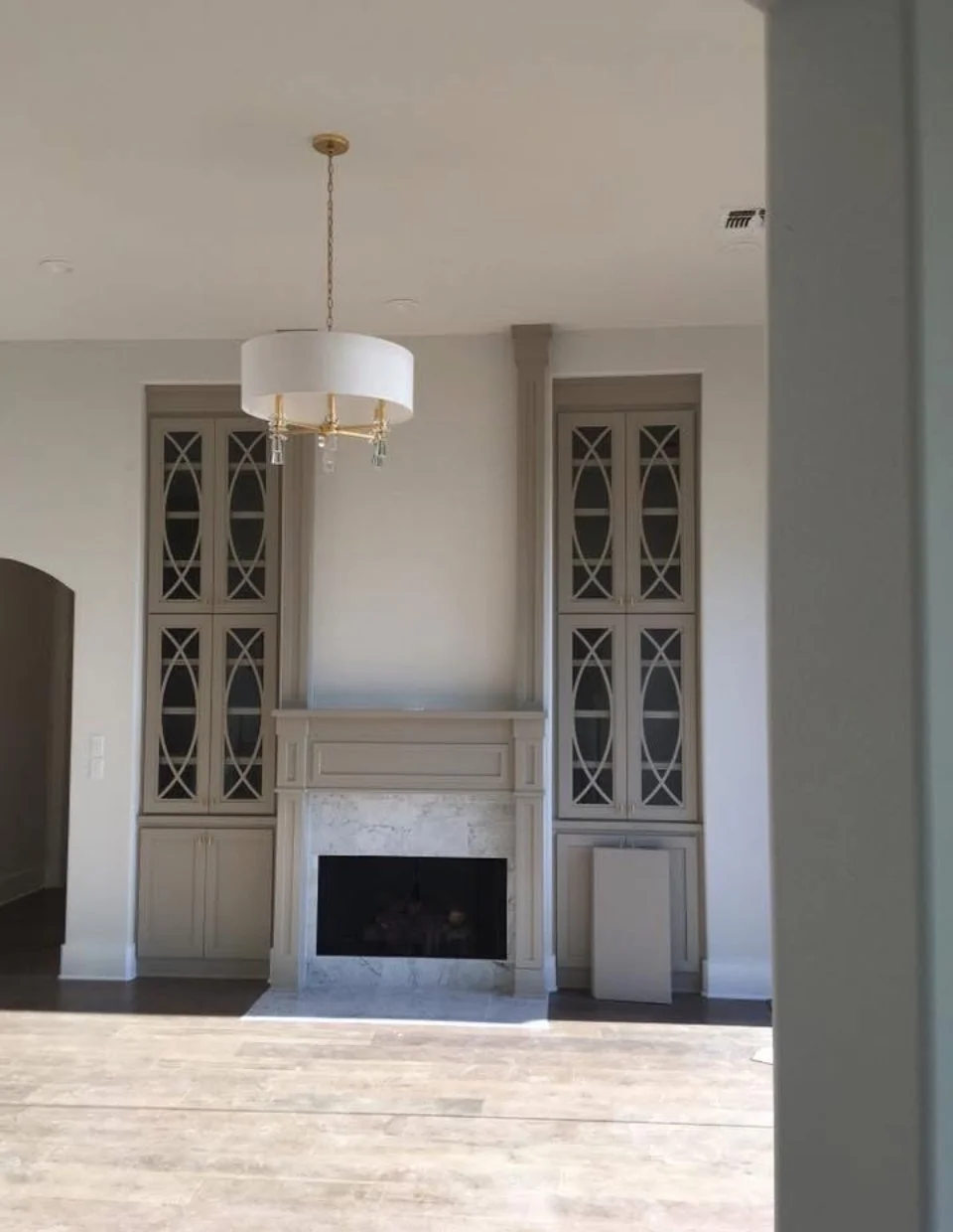 Living room with a fireplace, built-in cabinets on both sides, and a modern white chandelier hanging from the ceiling.