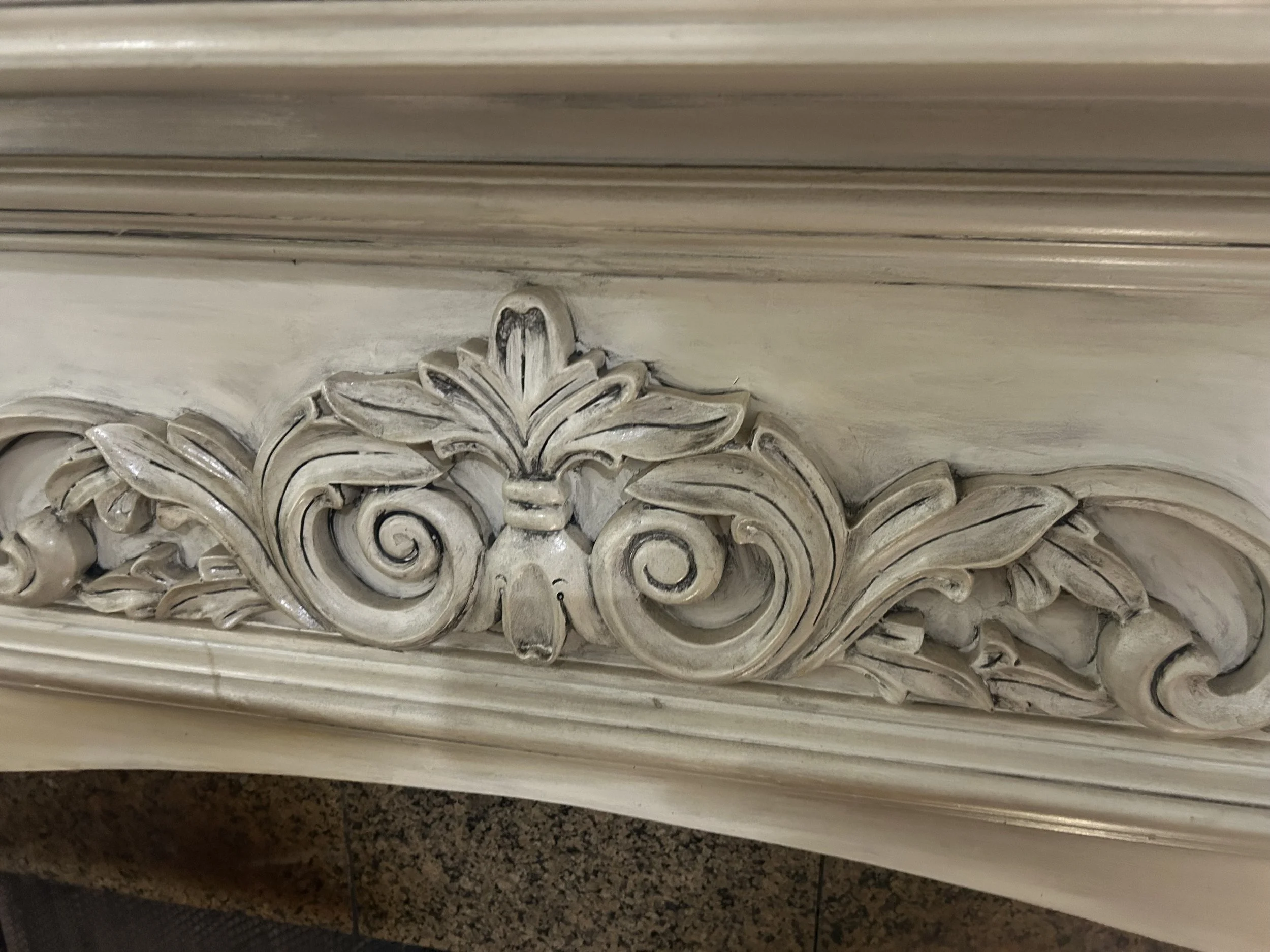 Ornate carved decorative wood piece with floral and scroll motifs, painted in a distressed white finish.