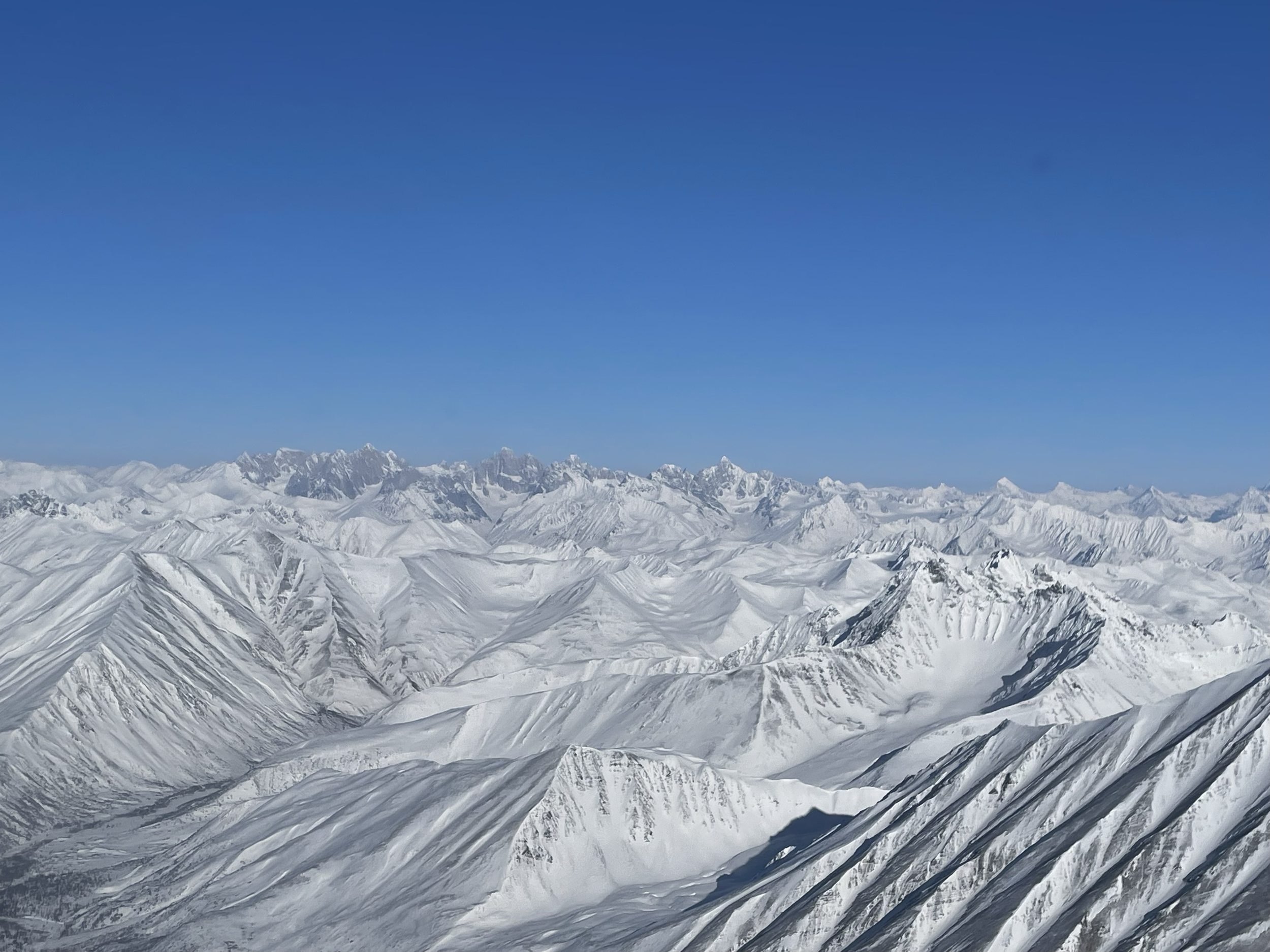 Snow-covered mountain range under a clear blue sky.