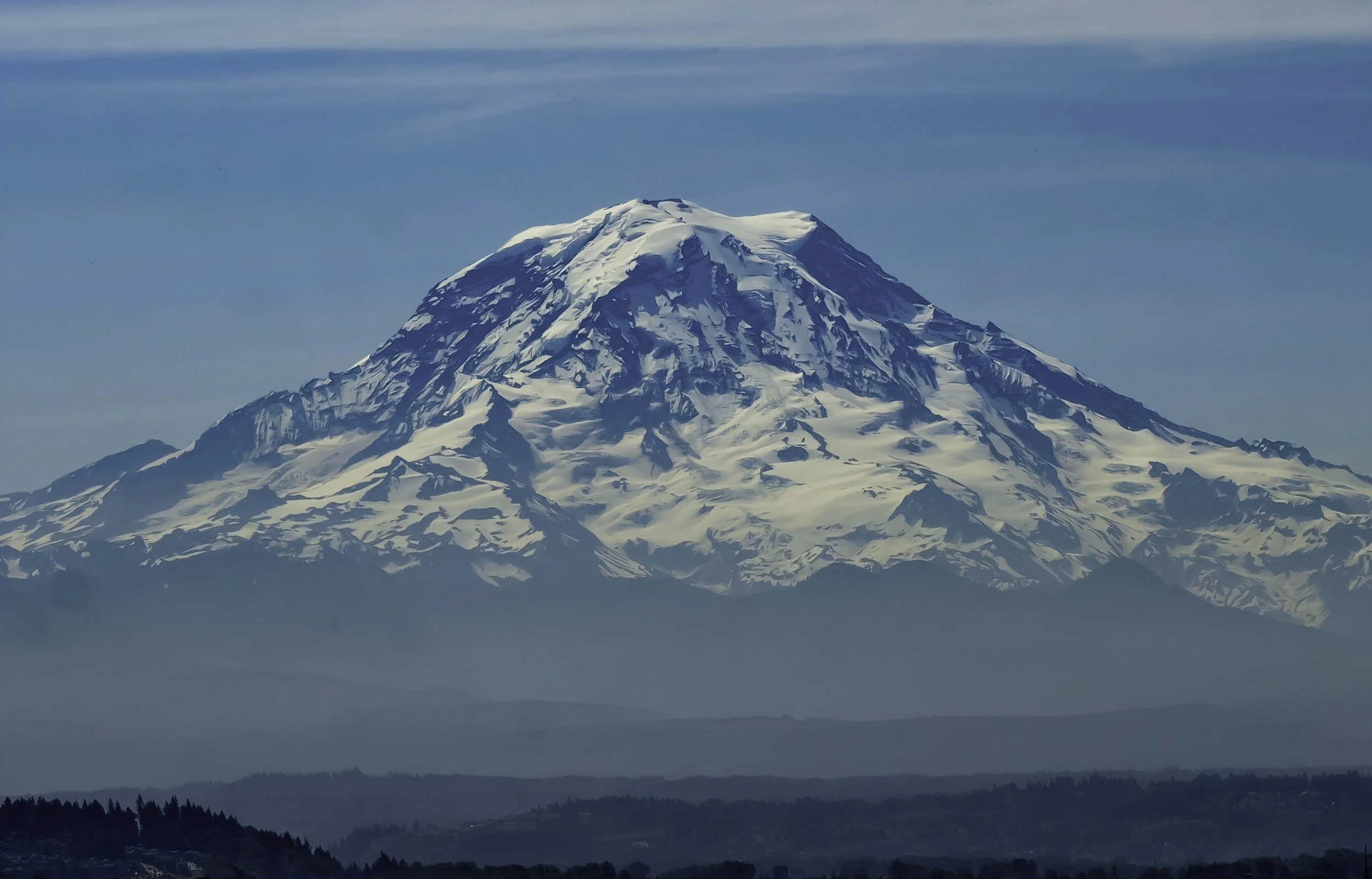 Snow-capped mountain with multiple ridges and clouds in the sky.