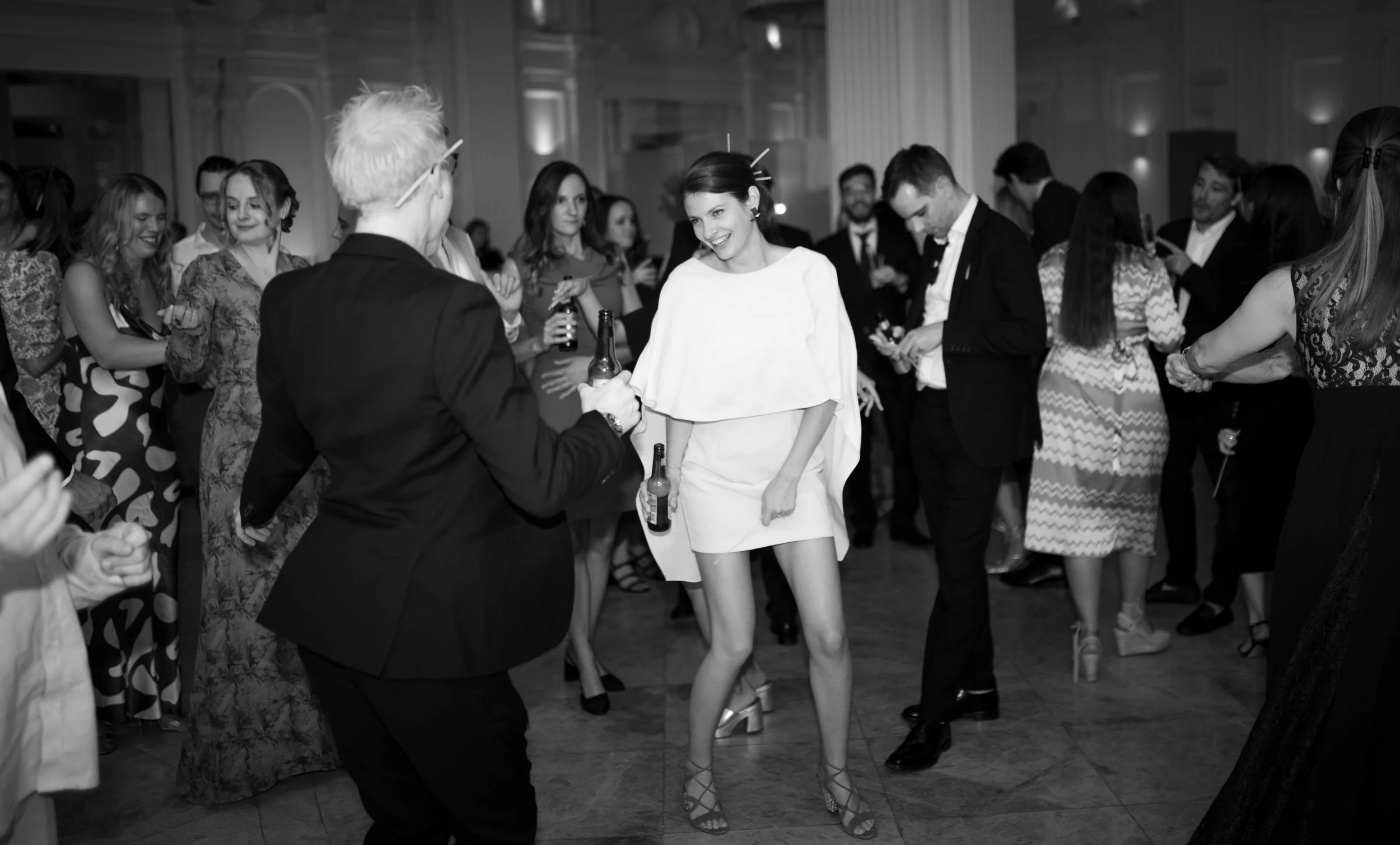 People dancing and celebrating at a party or wedding reception in an elegant venue.