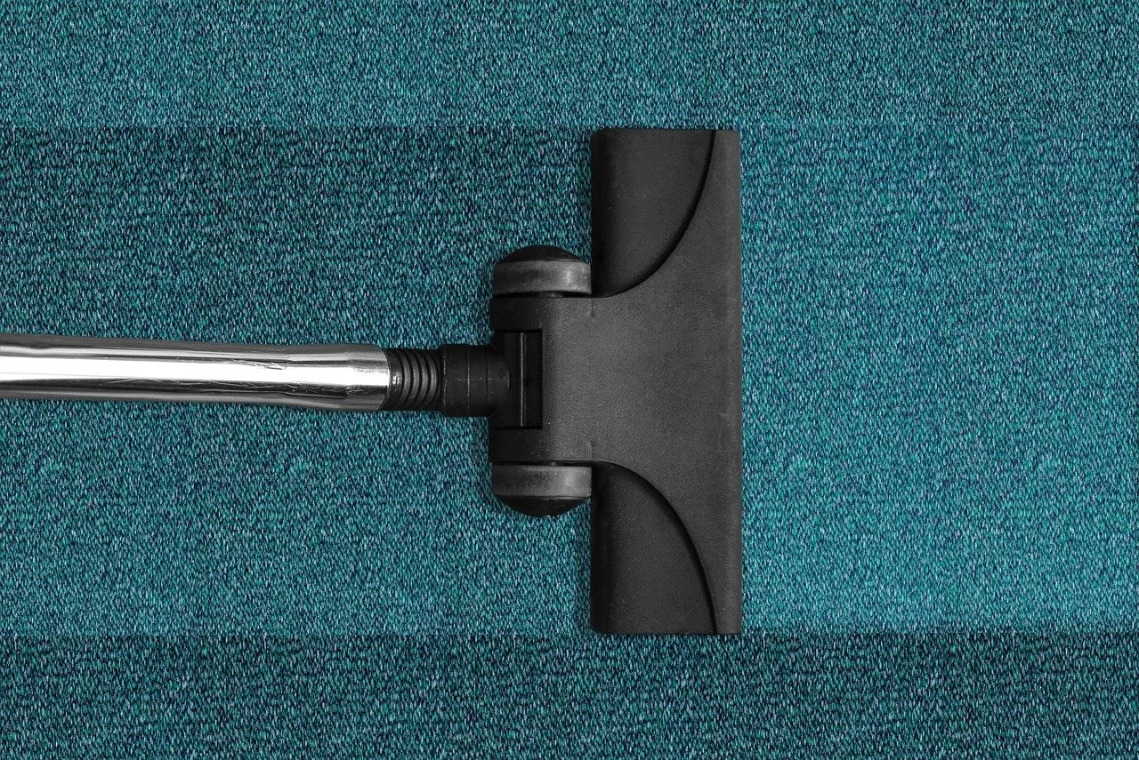 Close-up of a vacuum cleaner head on teal carpet.