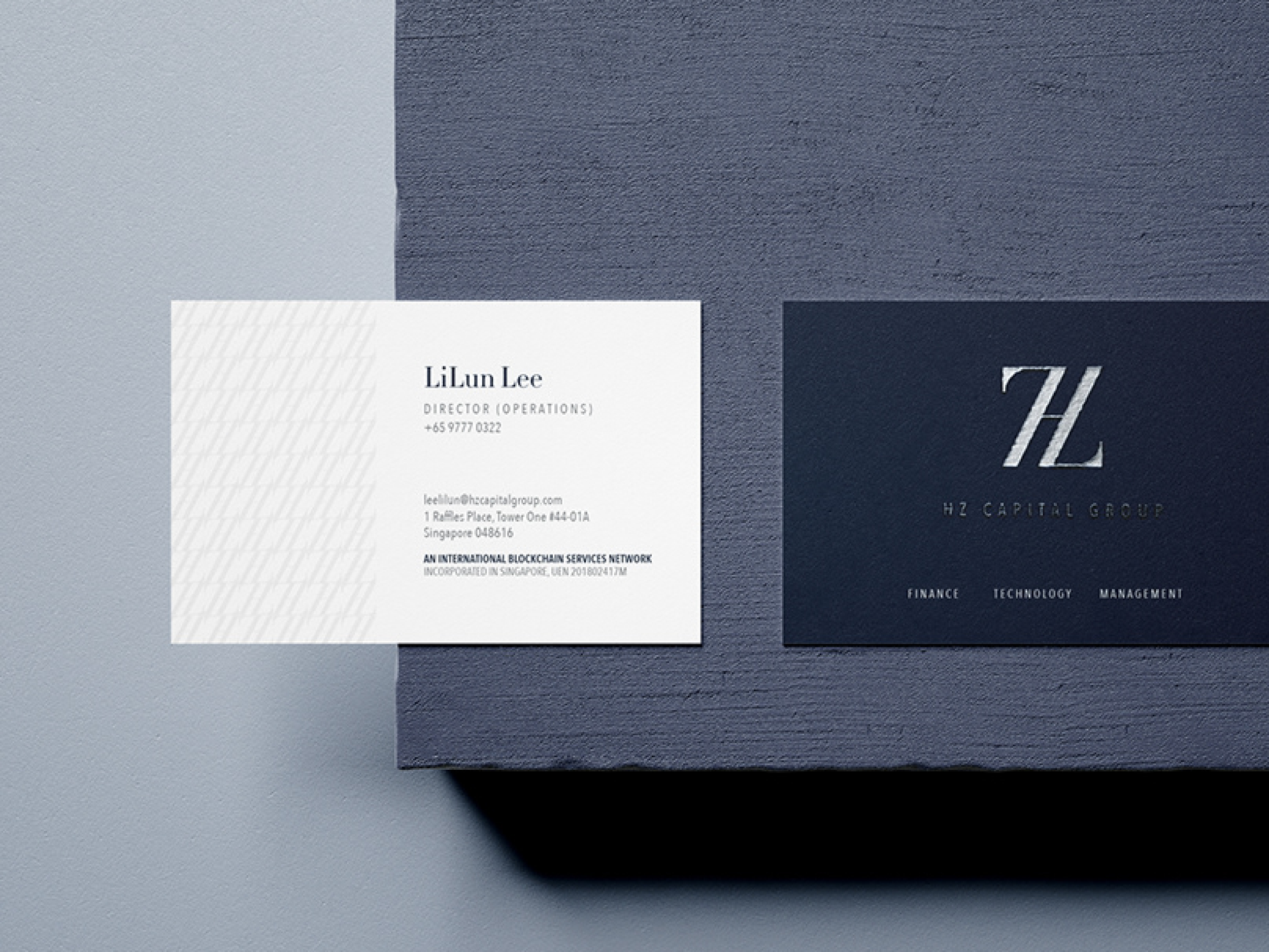 Business card for LiLun Lee, Director of Operations, with contact information, placed next to a dark blue and navy branding card with the logo 'HZ' for HZ Capital Group on textured surface.