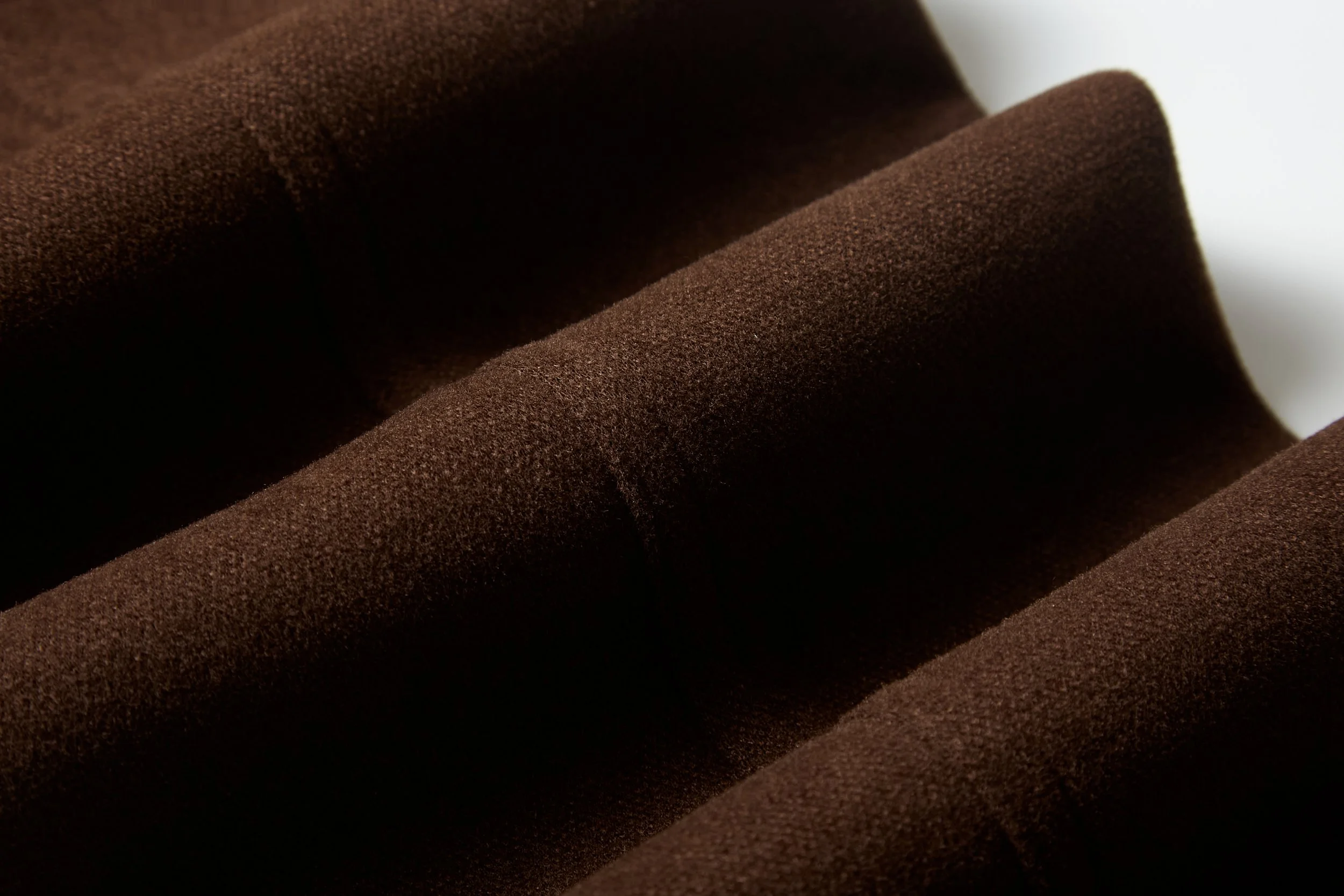 Close-up of brown fabric with a soft, textured surface and folded appearance.