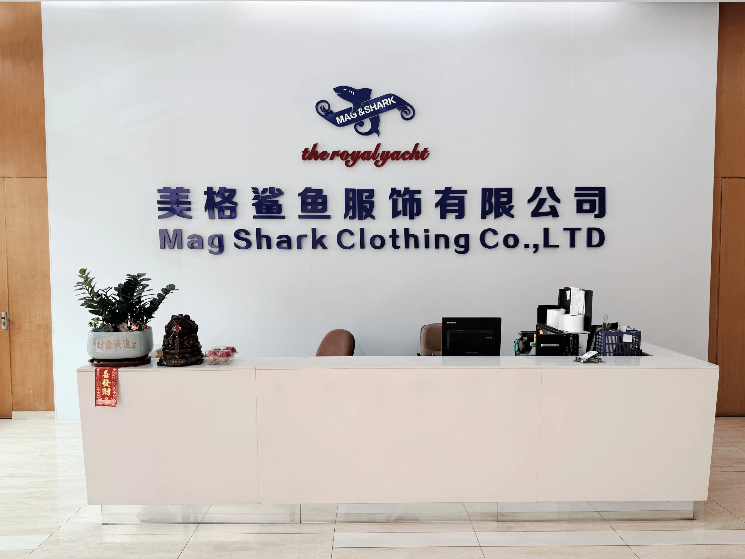 Reception desk at MAG SHARK Clothing Co., LTD with office supplies, and signage on the wall.