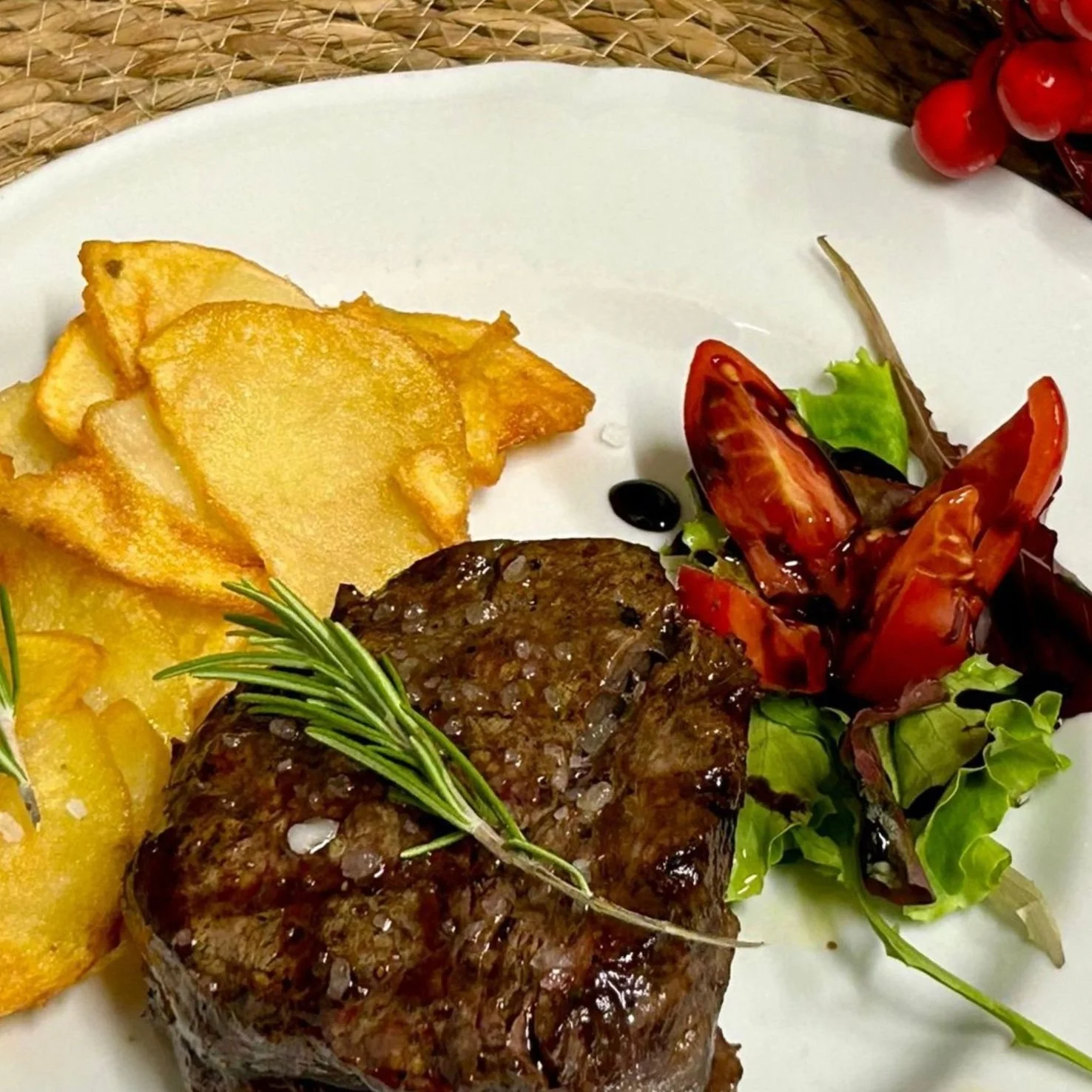 Piatti di carne con patate fritte e insalata mista con pomodori e foglie verdi.