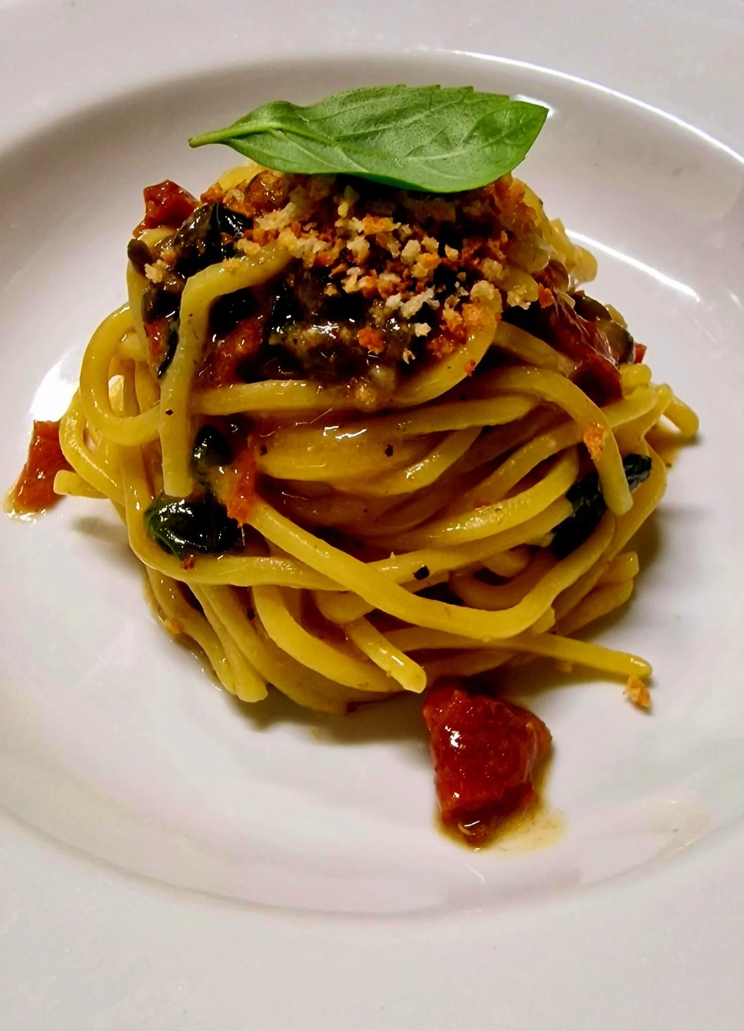 Piatto di spaghetti con pomodoro, basilico, e formaggio grattugiato.