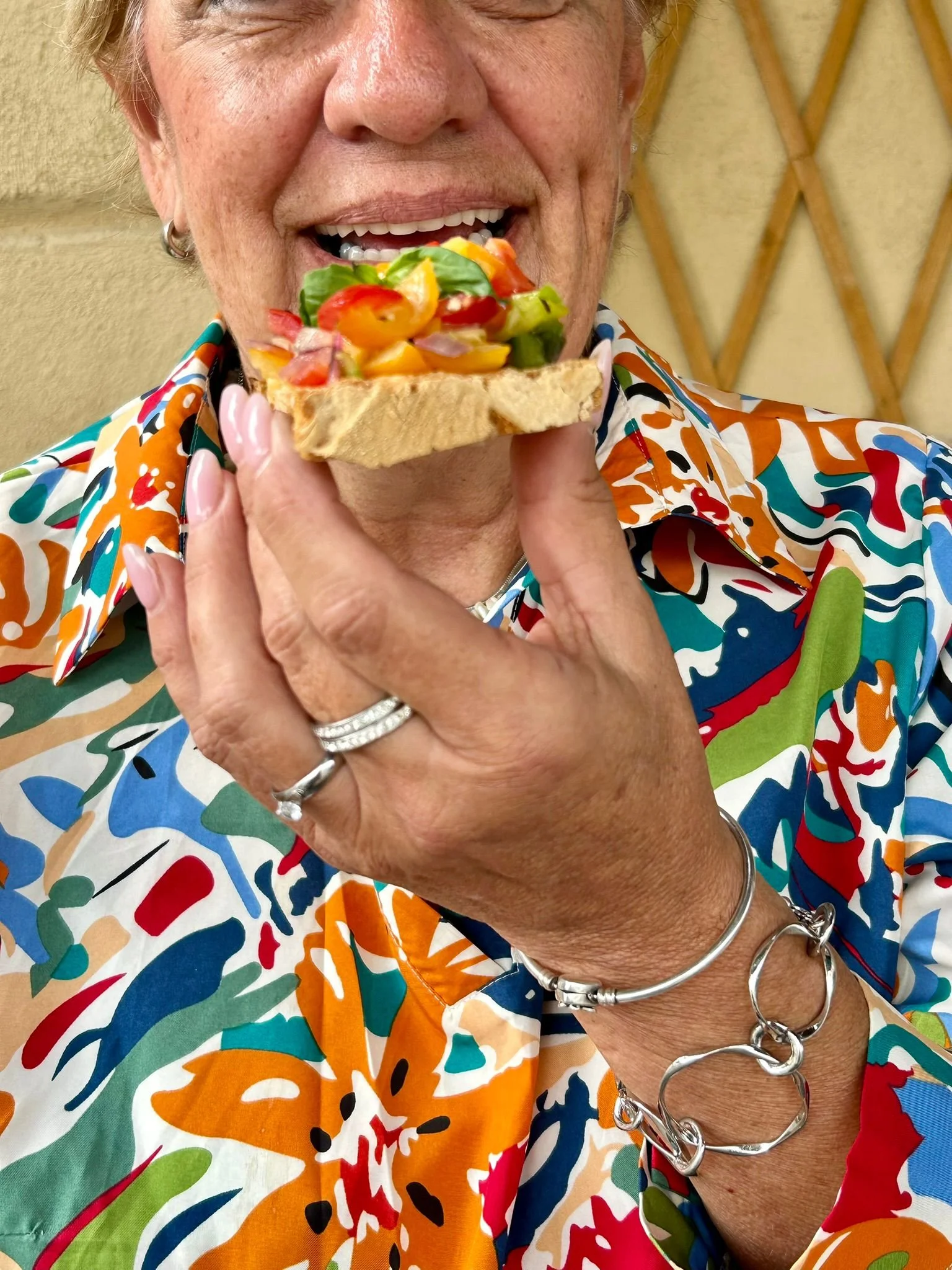 Donna anziana che si sta preparando a mangiare un crostino con insalata di verdure fresche.