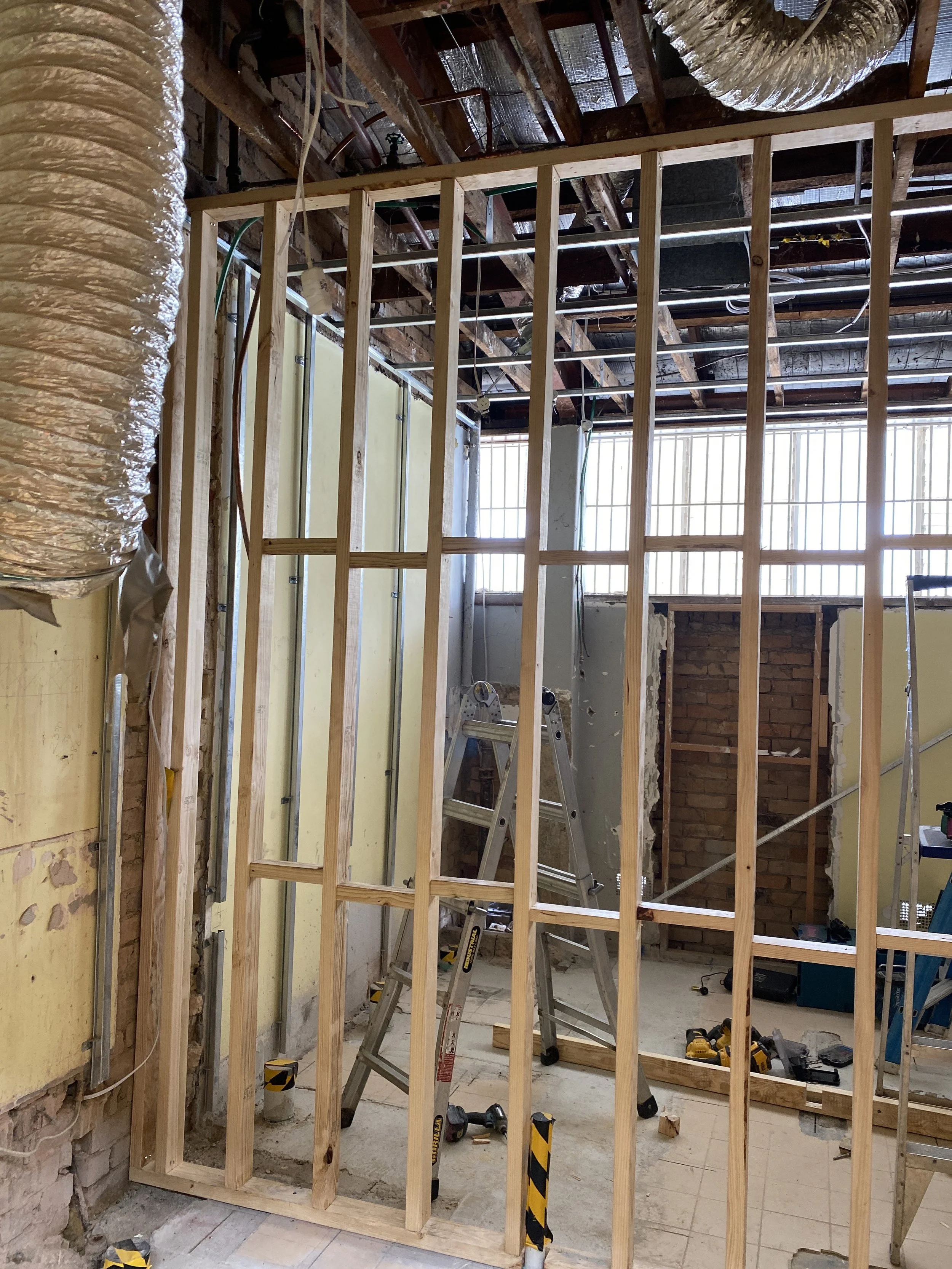 Interior of a house under construction with wooden framing, exposed ceiling beams, and construction tools.