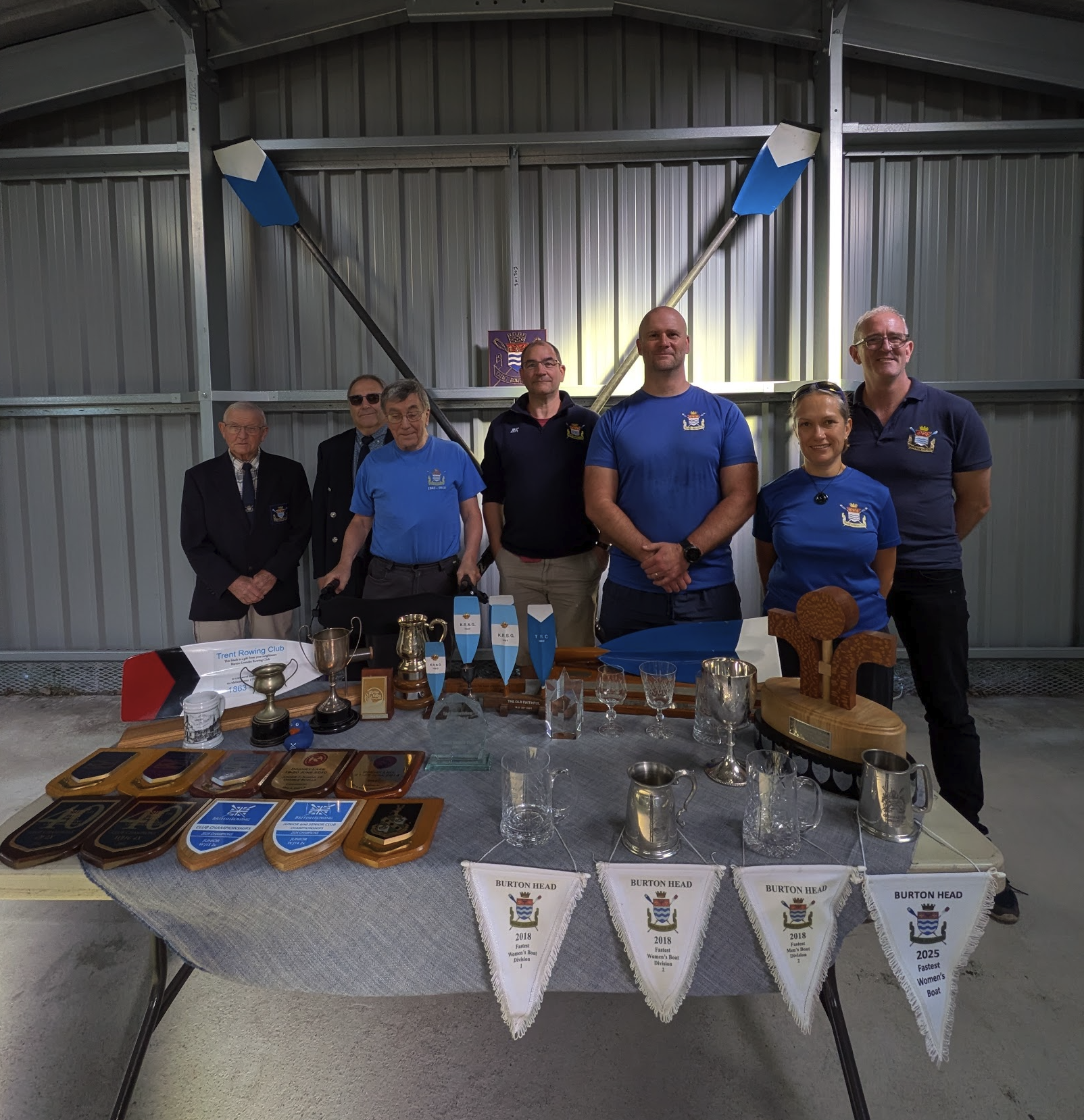 Trent Rowing Club committee members with club trophies and awards inside the new Boat Barn