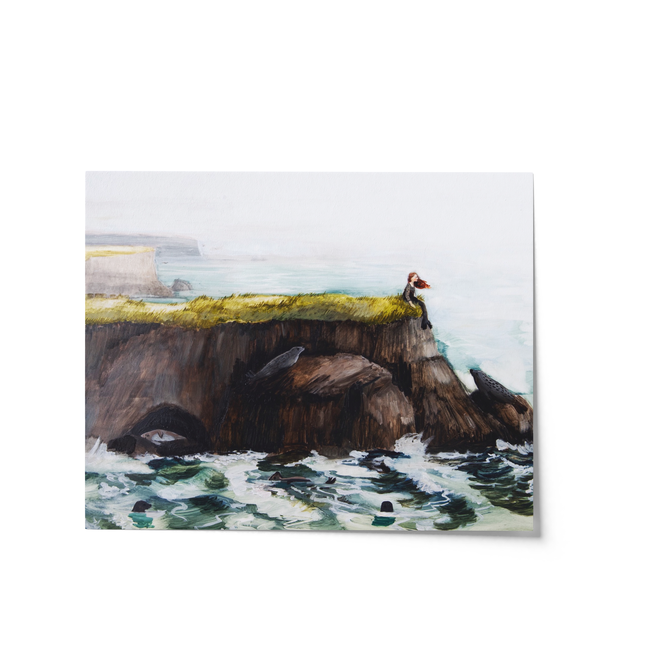 Painting of a red-haired woman sitting on a grassy cliff above crashing waves, surrounded by seals – selkie folklore art by Briana Corr Scott