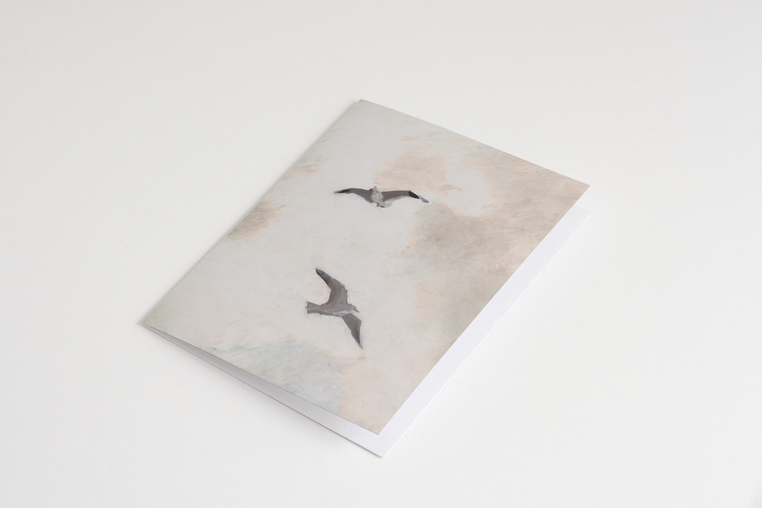 Greeting card featuring two seagulls flying through a soft, painterly coastal sky in muted tones – folded A2 card illustrated by Briana Corr Scott