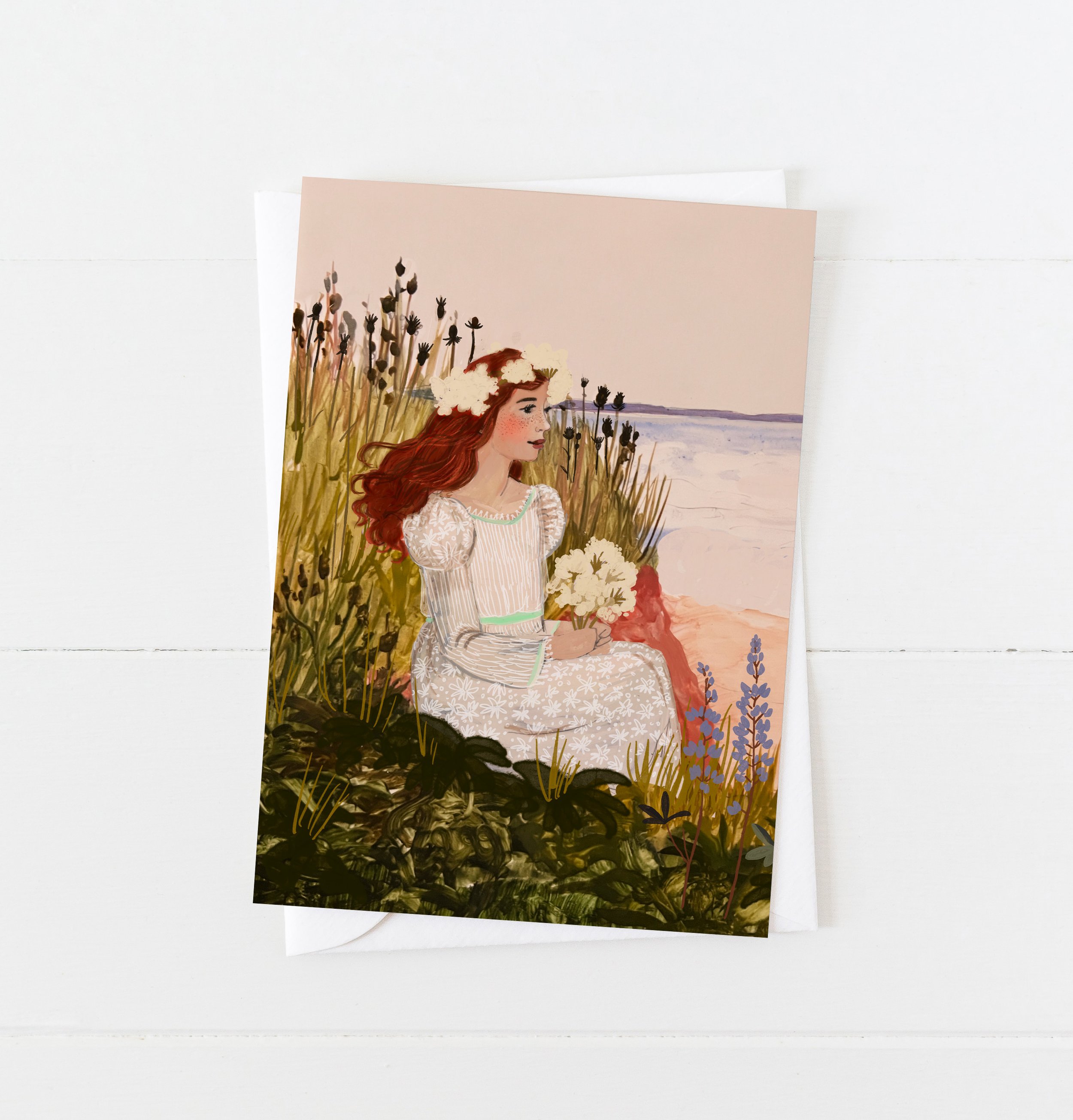 Anne of Green Gables sitting in a coastal meadow holding white flowers, wearing a floral dress and crown, with the sea in the background – artwork by Briana Corr Scott