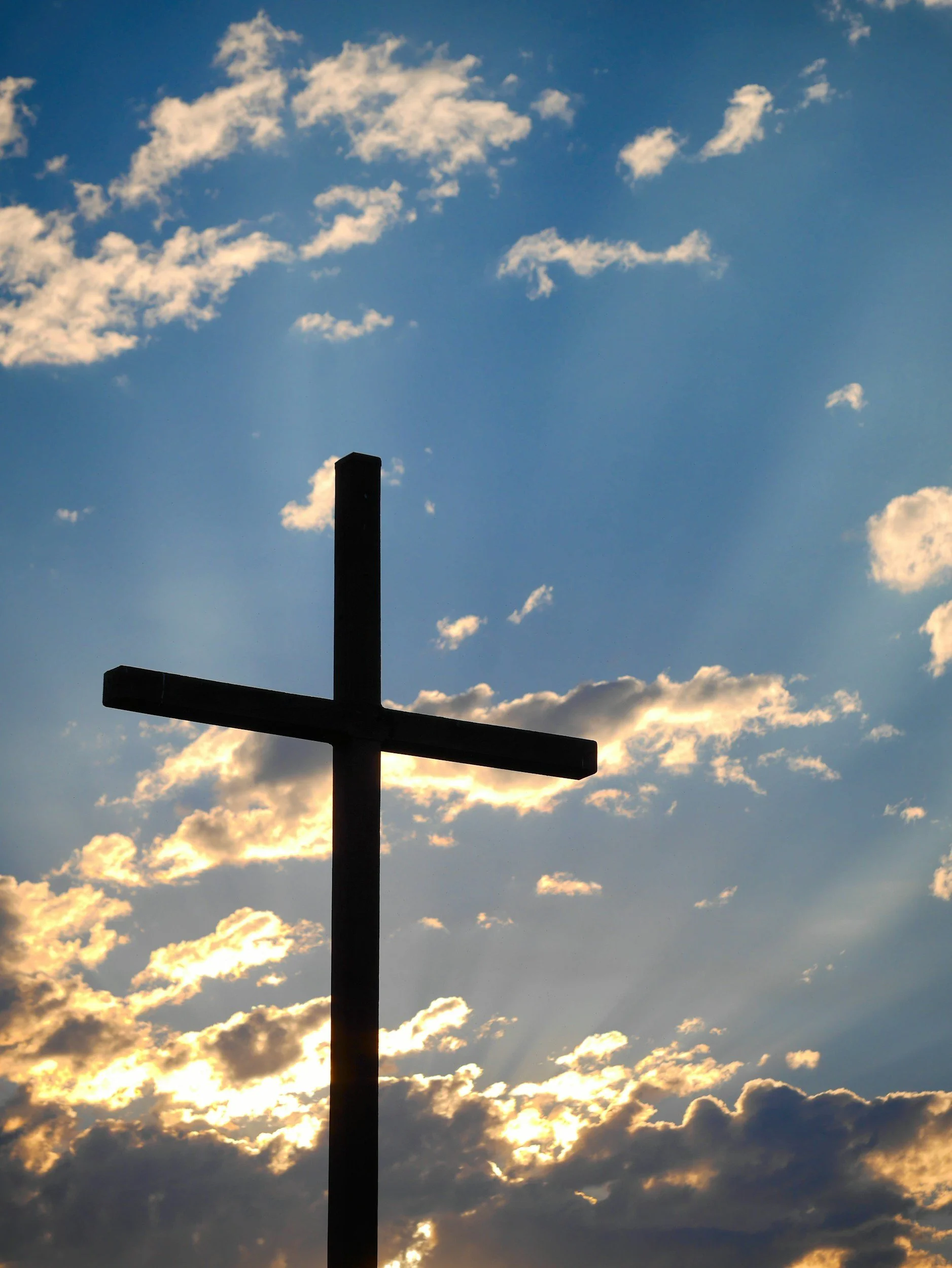 cross against blue sky with clouds