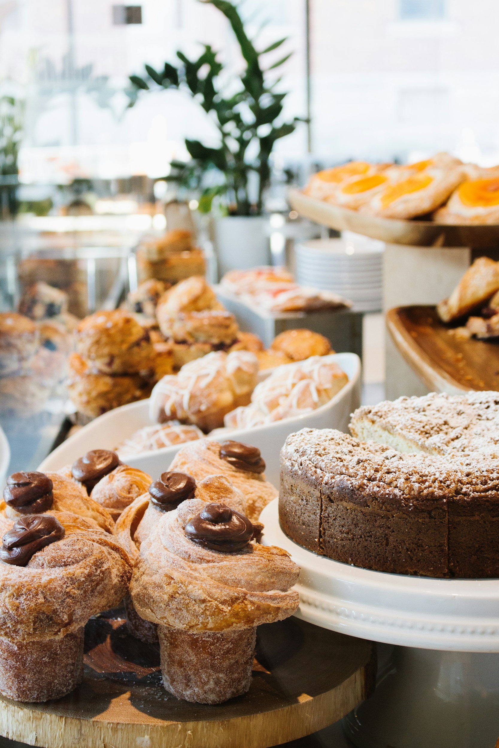 Assorted baked goods including pastries, cookies, and a chocolate cake on display in a bakery setting.