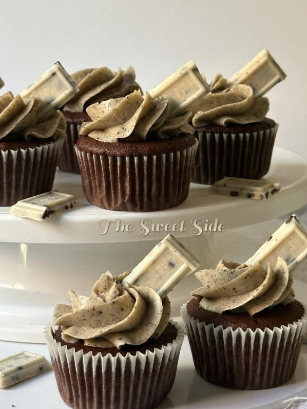 Chocolate cupcakes topped with cookies and cream frosting and white chocolate pieces, arranged on a white plate.