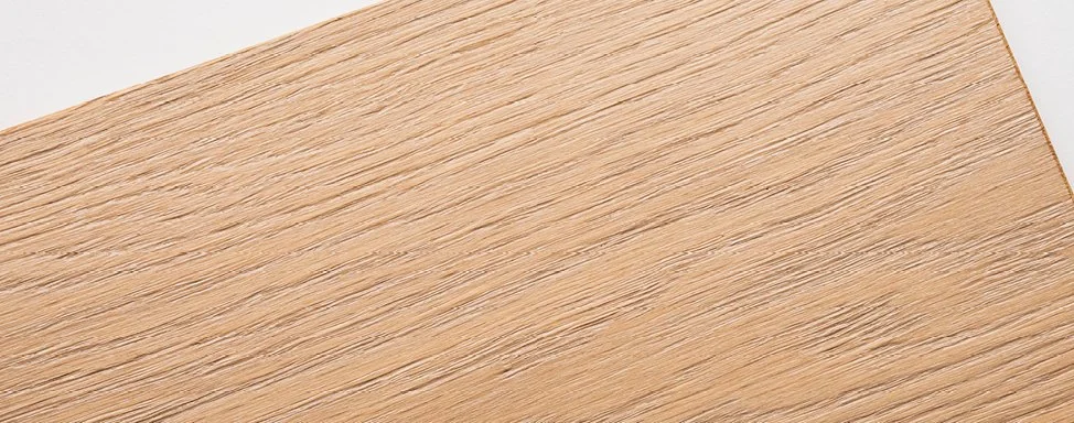 Nahaufnahme einer Holzoberfläche mit sichtbarer Maserung und Kantenansicht, helle Holzfarbe.