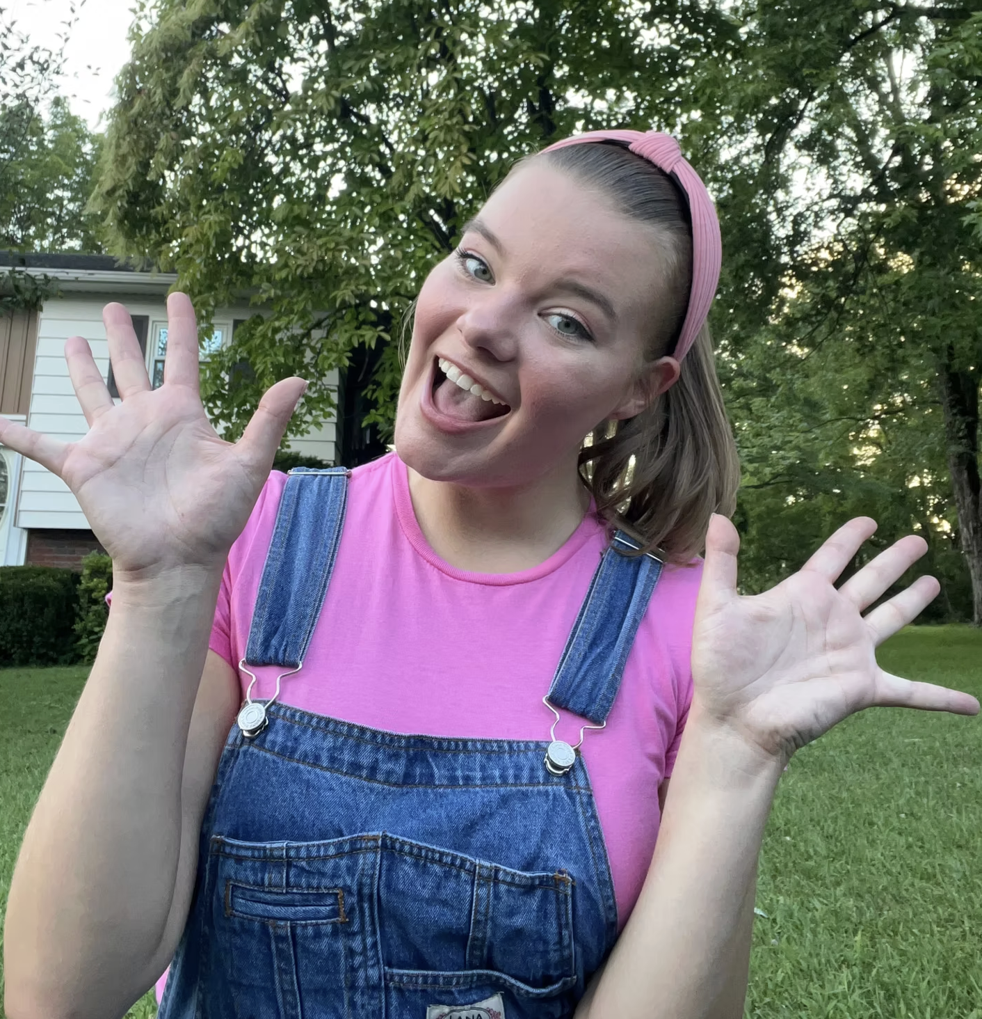 A young woman dressed as Miss Rachel with trees and a house in the background.