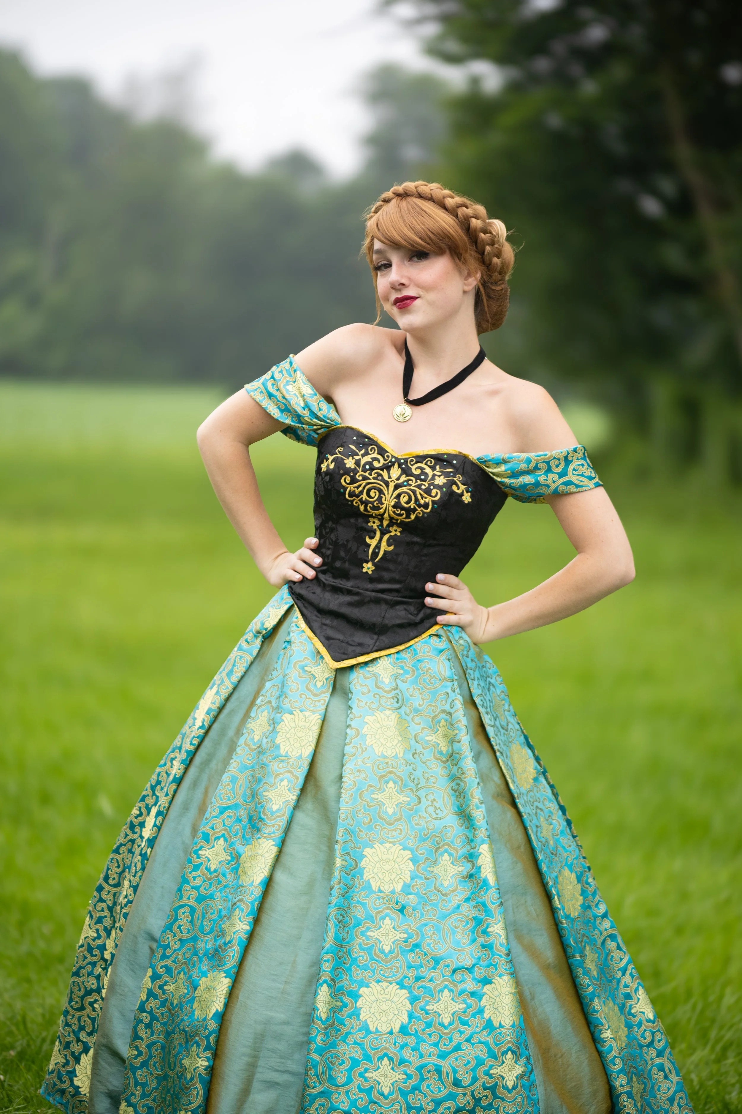 A woman in a colorful, ornate costume standing outdoors in a grassy field with trees in the background, inspired by Princess Anna.
