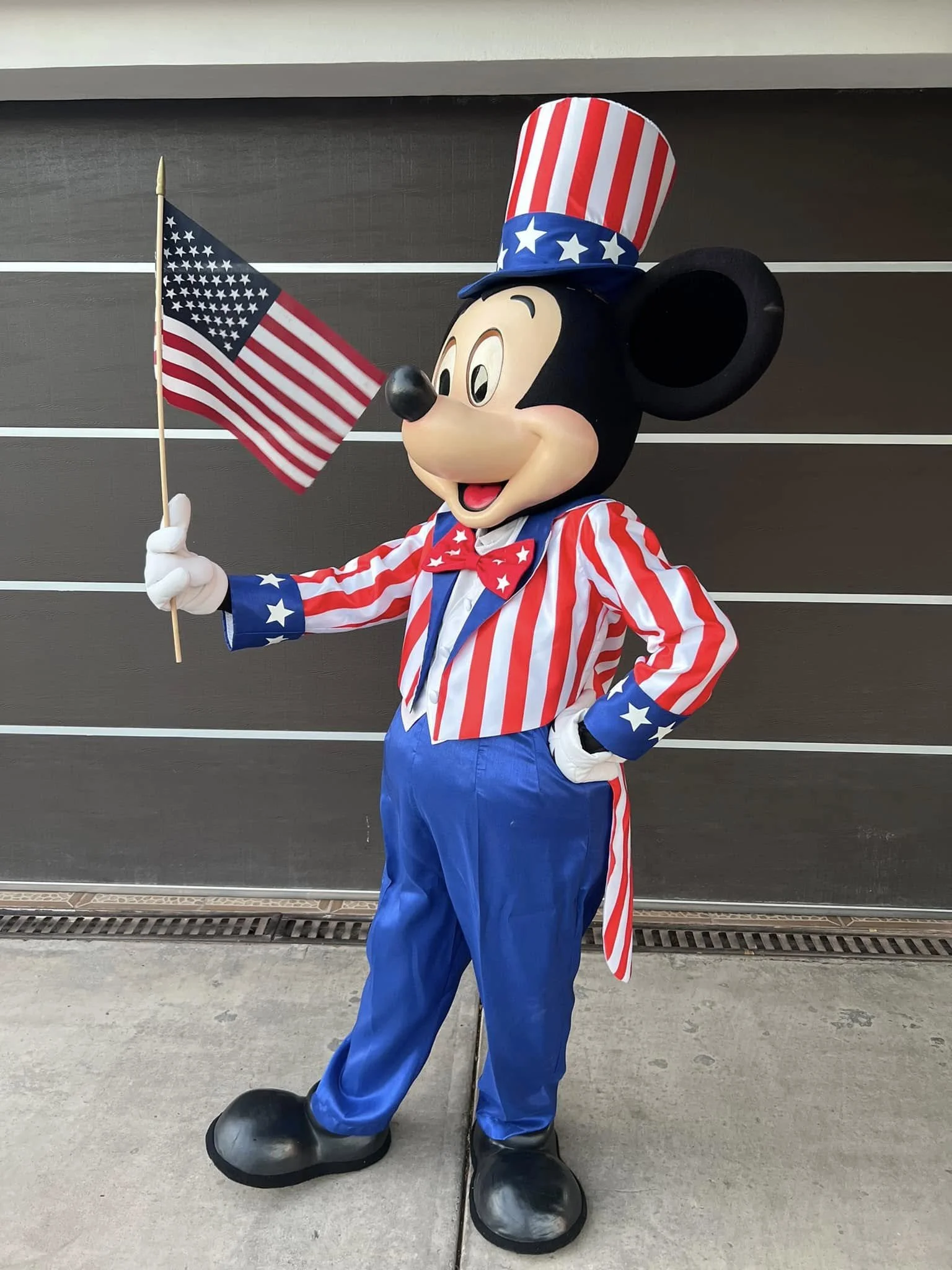 Mickey Mouse dressed in an American patriotic outfit, holding an American flag.