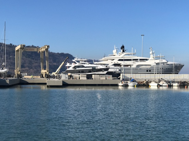 Large luxury yachts docked at a marina with a clear blue sky in the background