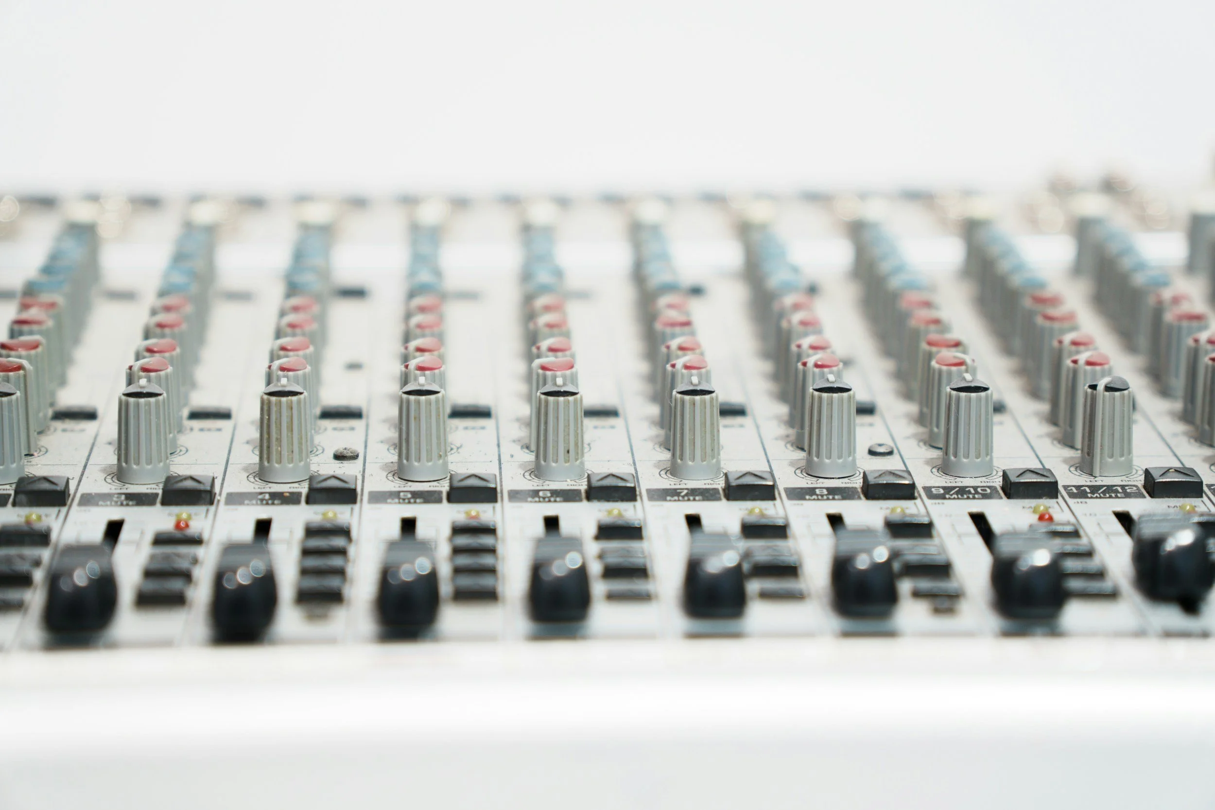Close-up of a professional audio mixing console with numerous knobs, sliders, and controls.
