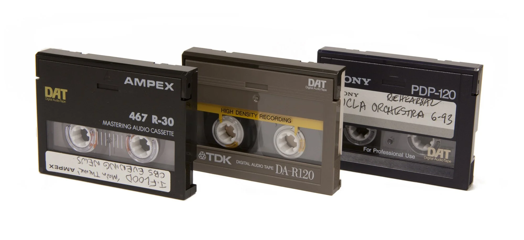 Three vintage audio cassette tapes lined up, labeled as Mastering Audio Cassette, High Density Recording, and Rehearsal, with handwritten notes and brand names such as Ampex, TDK, and Sony.