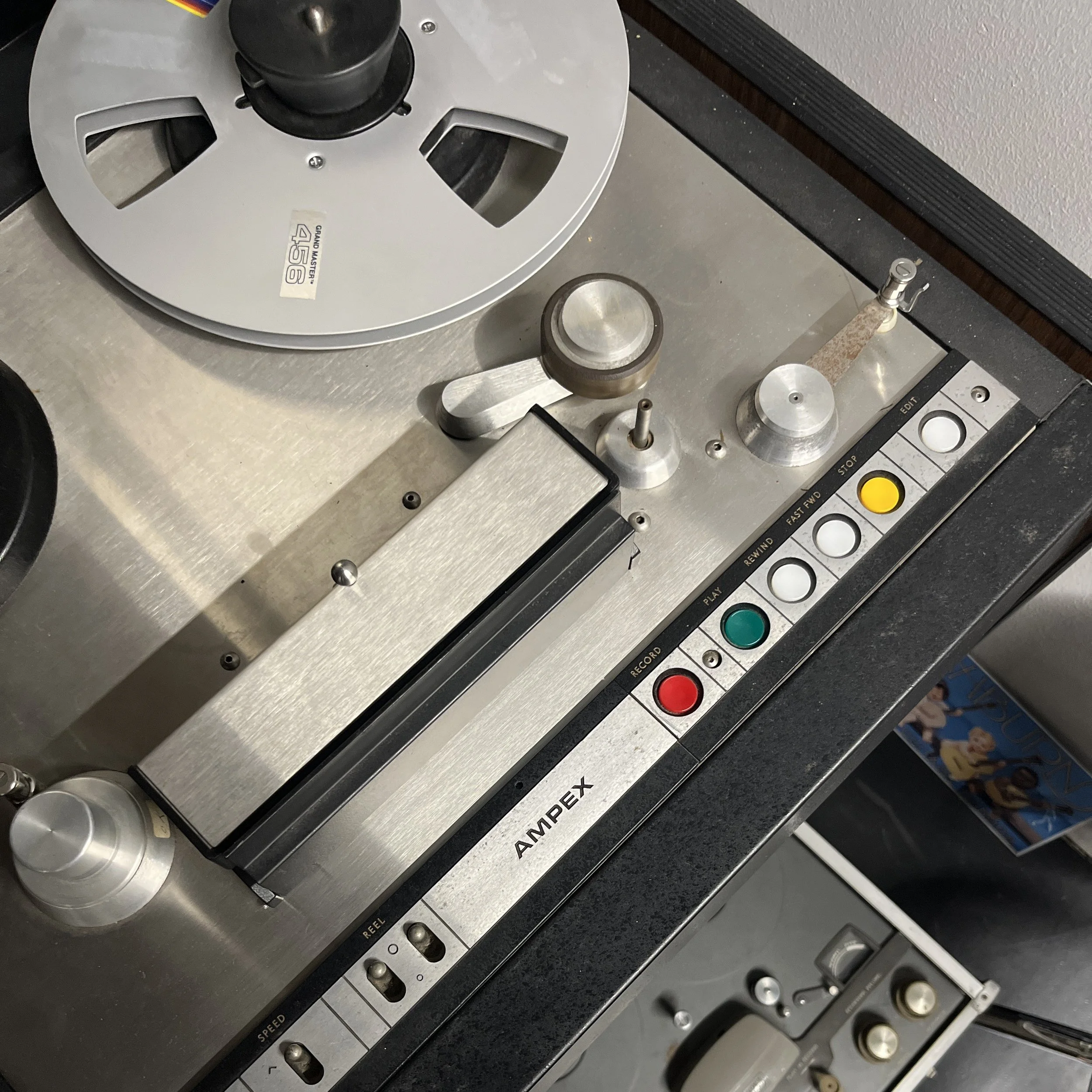 Close-up of a vintage Ampex reel-to-reel tape recorder with buttons, knobs, and reels.