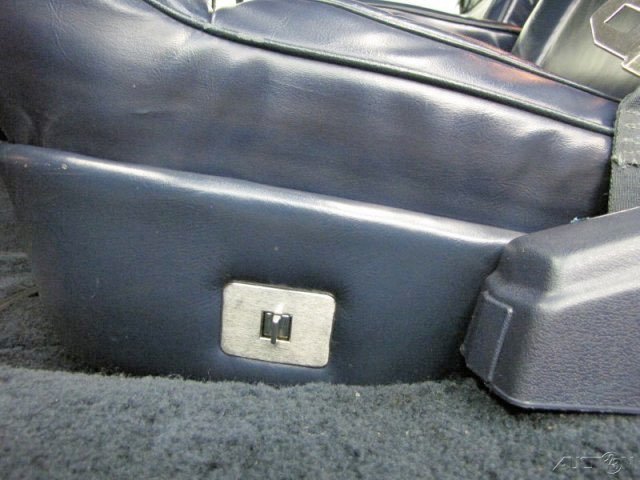 View of a car's interior seat with a power outlet on the side panel near the floor