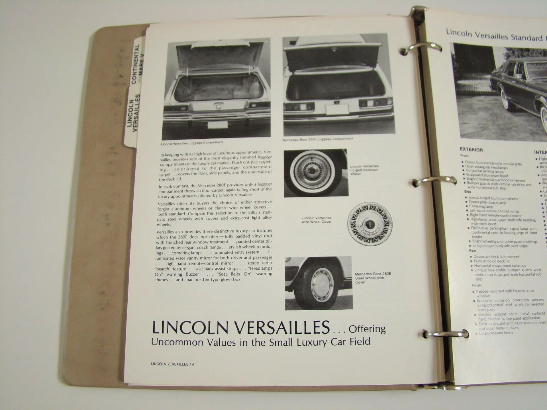 Open booklet with black and white photos of luggage compartments, wheels, and cars, describing features of Lincoln Versailles luxury car.