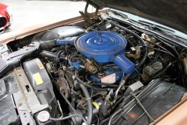 Car engine with a blue air cleaner, surrounded by hoses and components.