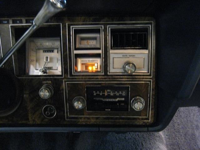 Dashboard of a vintage car featuring a speedometer, warning lights, a radio, and various control knobs