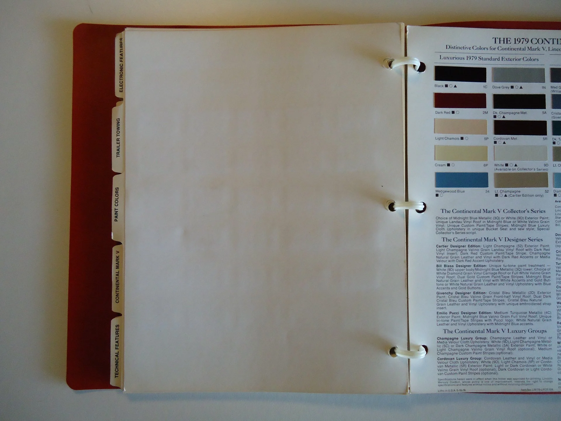 Open color sample book showing various paint colors and categories on the right side, with blank pages on the left, and red cover with white tabs along the left edge.