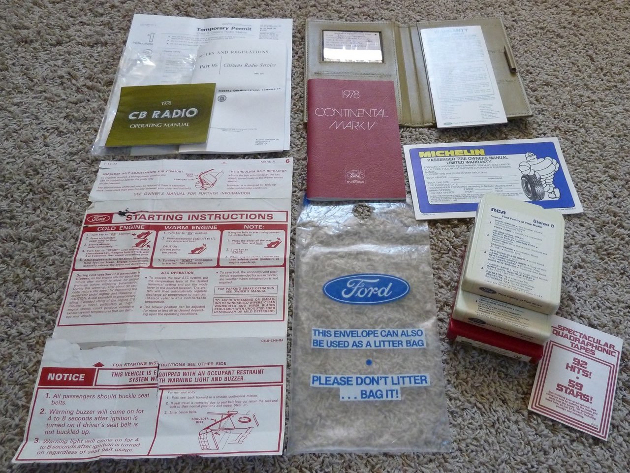 Collection of vintage car manuals, safety instructions, and informational pamphlets, including Ford, Michelin, and CB Radio operating manual, laid out on a carpet.